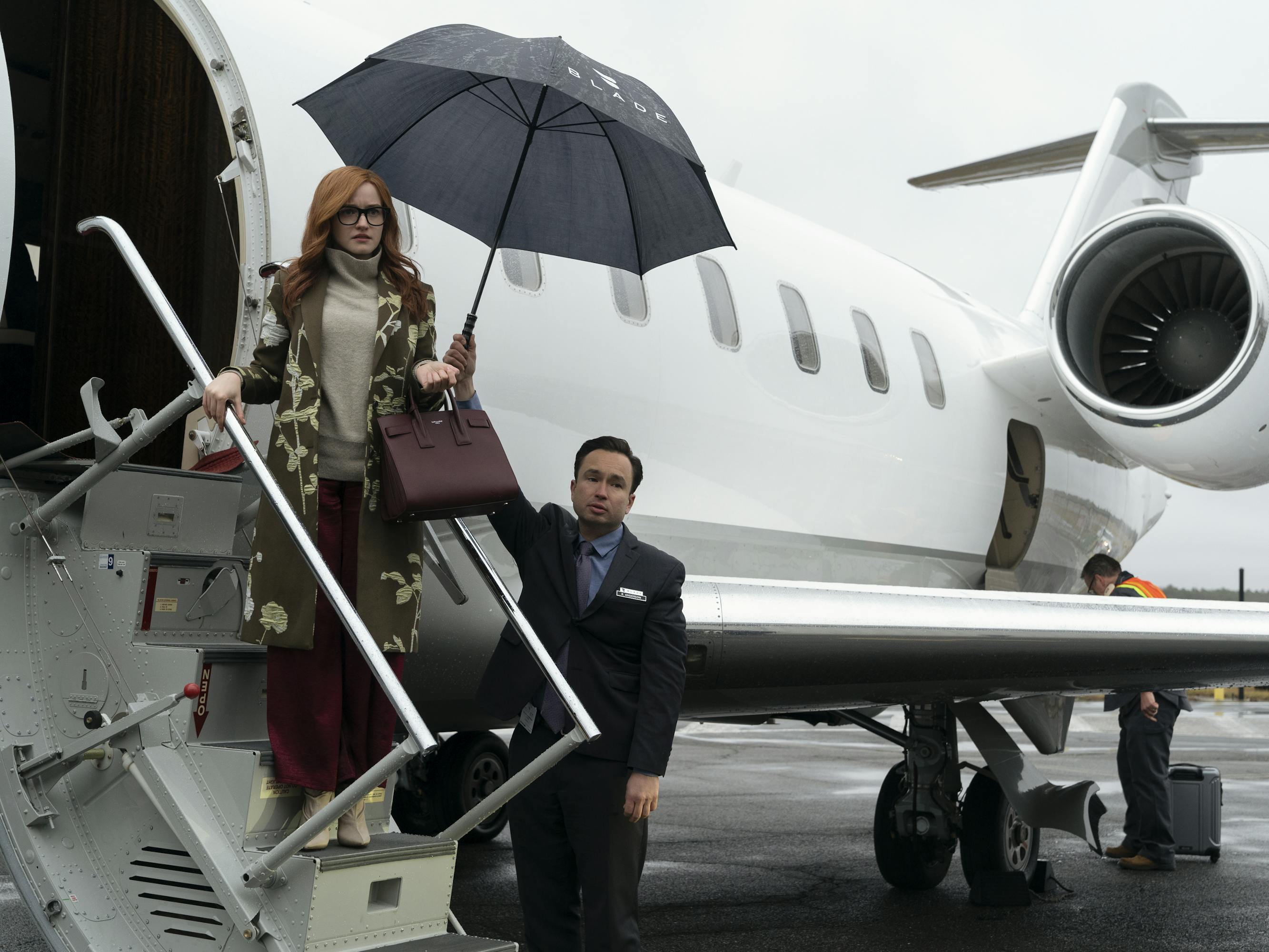 Julia Garner dismounts a private plane with a massive black umbrella.