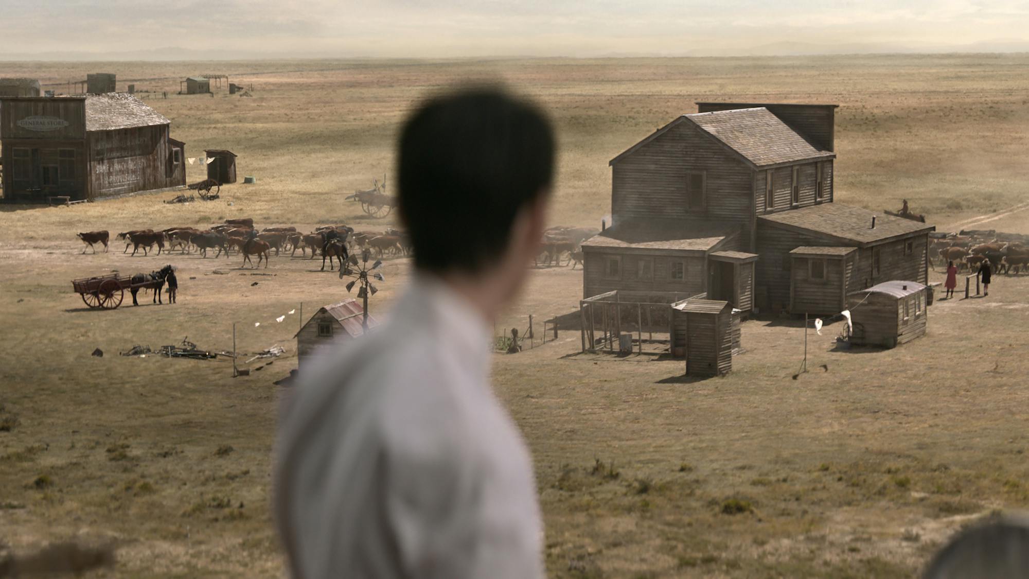 Peter Gordon (Kodi Smit-McPhee) stands in the middle of a dusty ranch. He looks over at some barns, animals, and people.