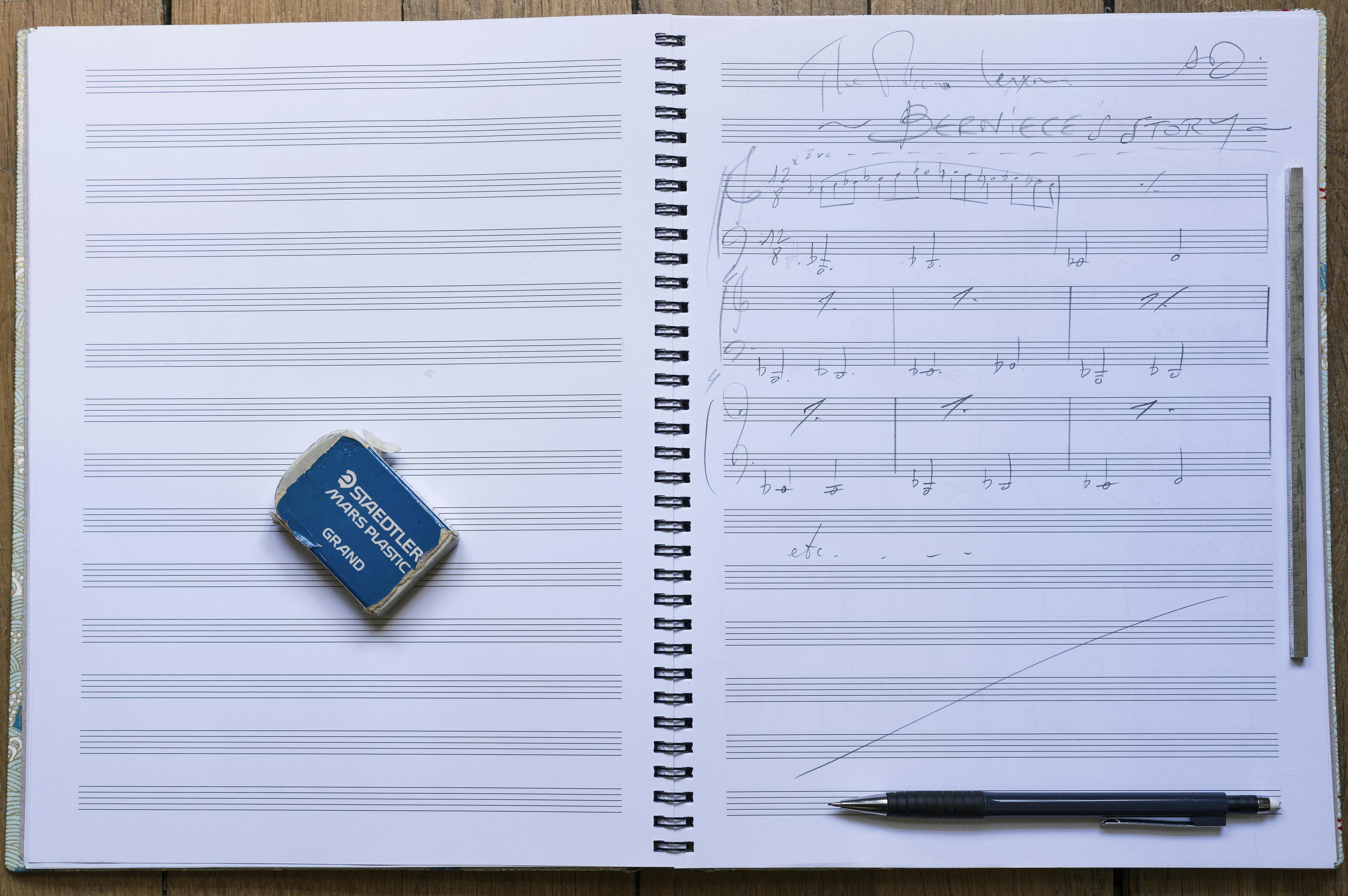 A portrait of a score book, framed by a blue eraser and pen.