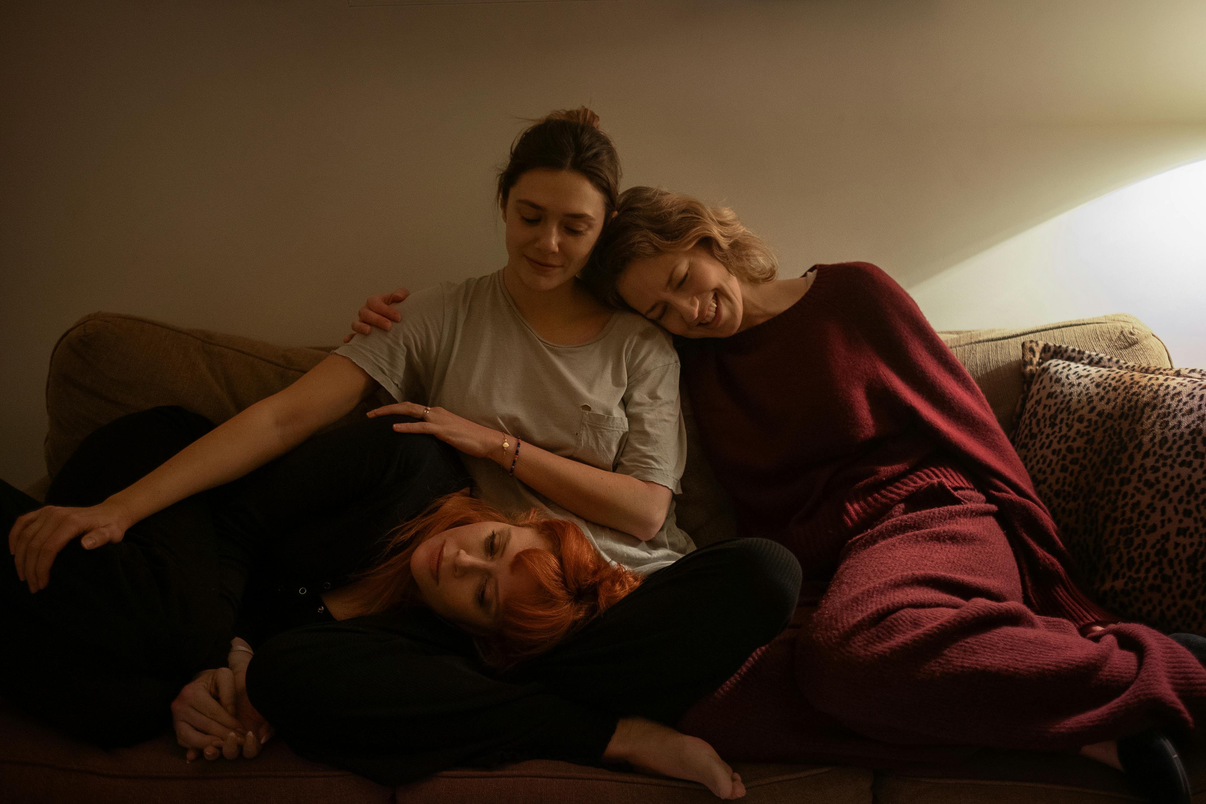 Christina (Elizabeth Olsen), Rachel (Natasha Lyonne), and Katie (Carie Coon) sit together on the couch.