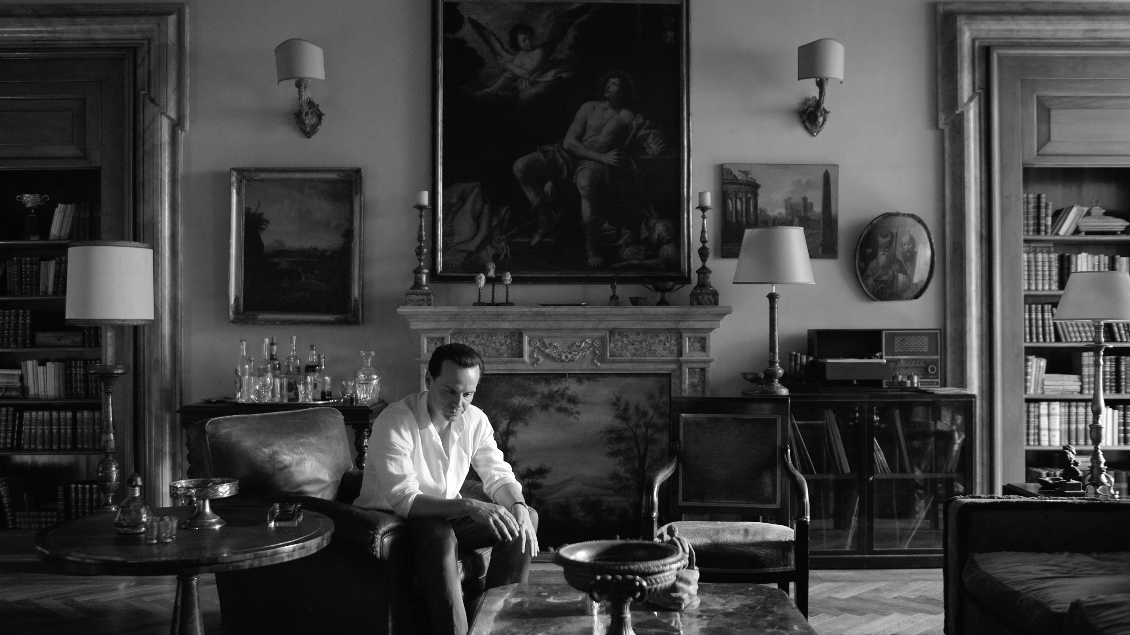 Tom Ripley (Andrew Scott) sits in a living room in a white shirt.