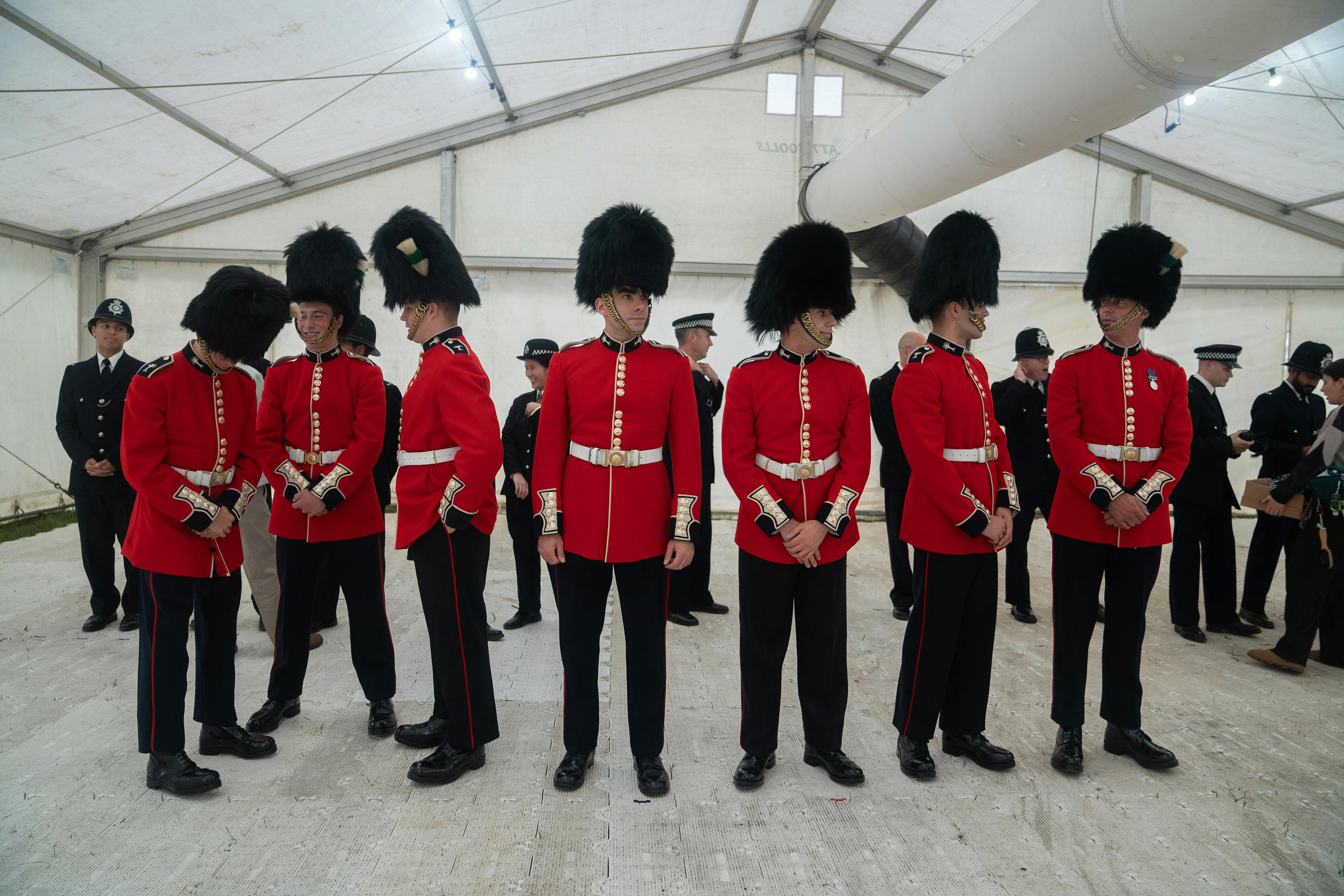 Some actors playing bobbies stand around in a white room.