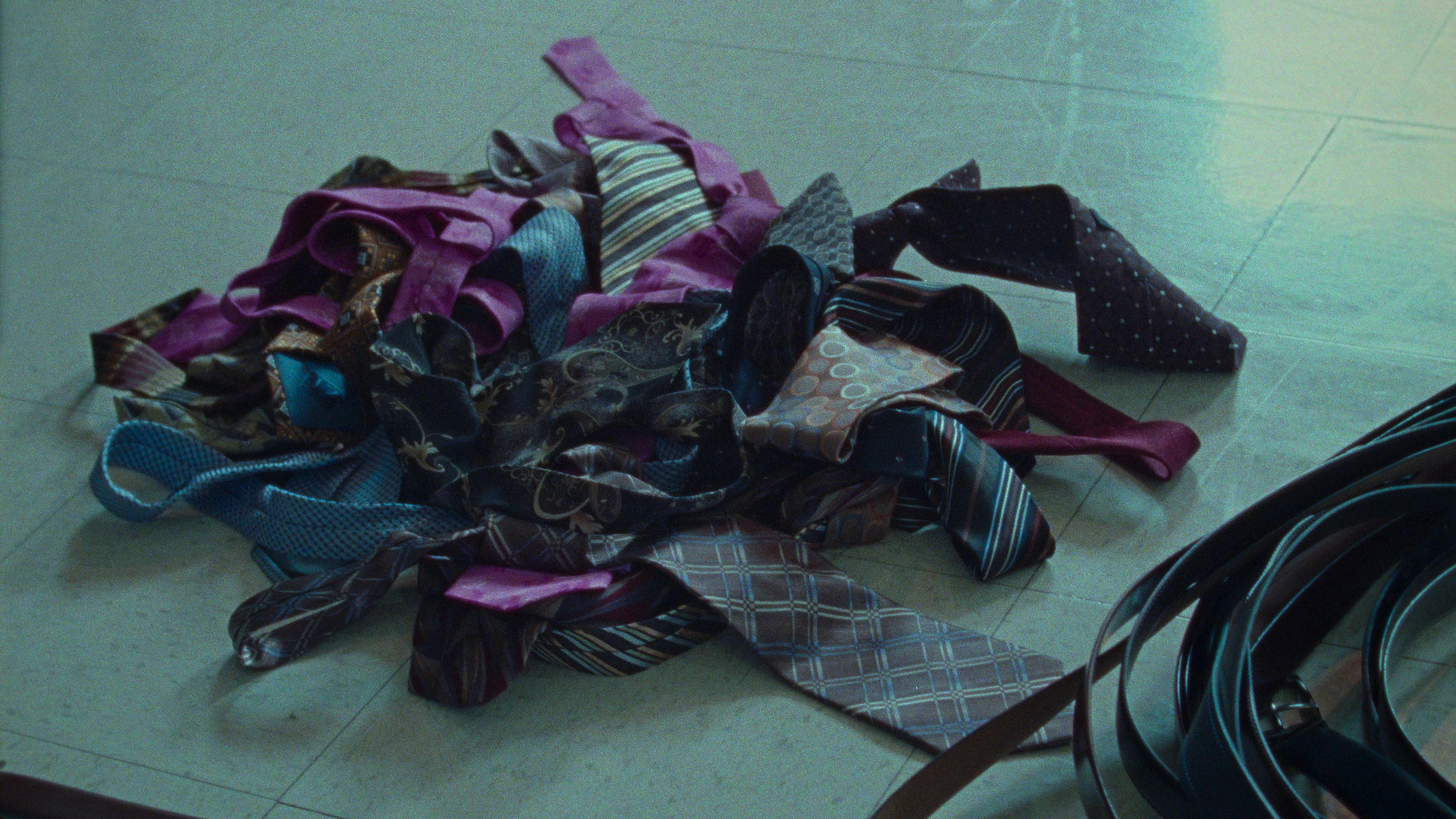 A pile of ties on a linoleum floor. 