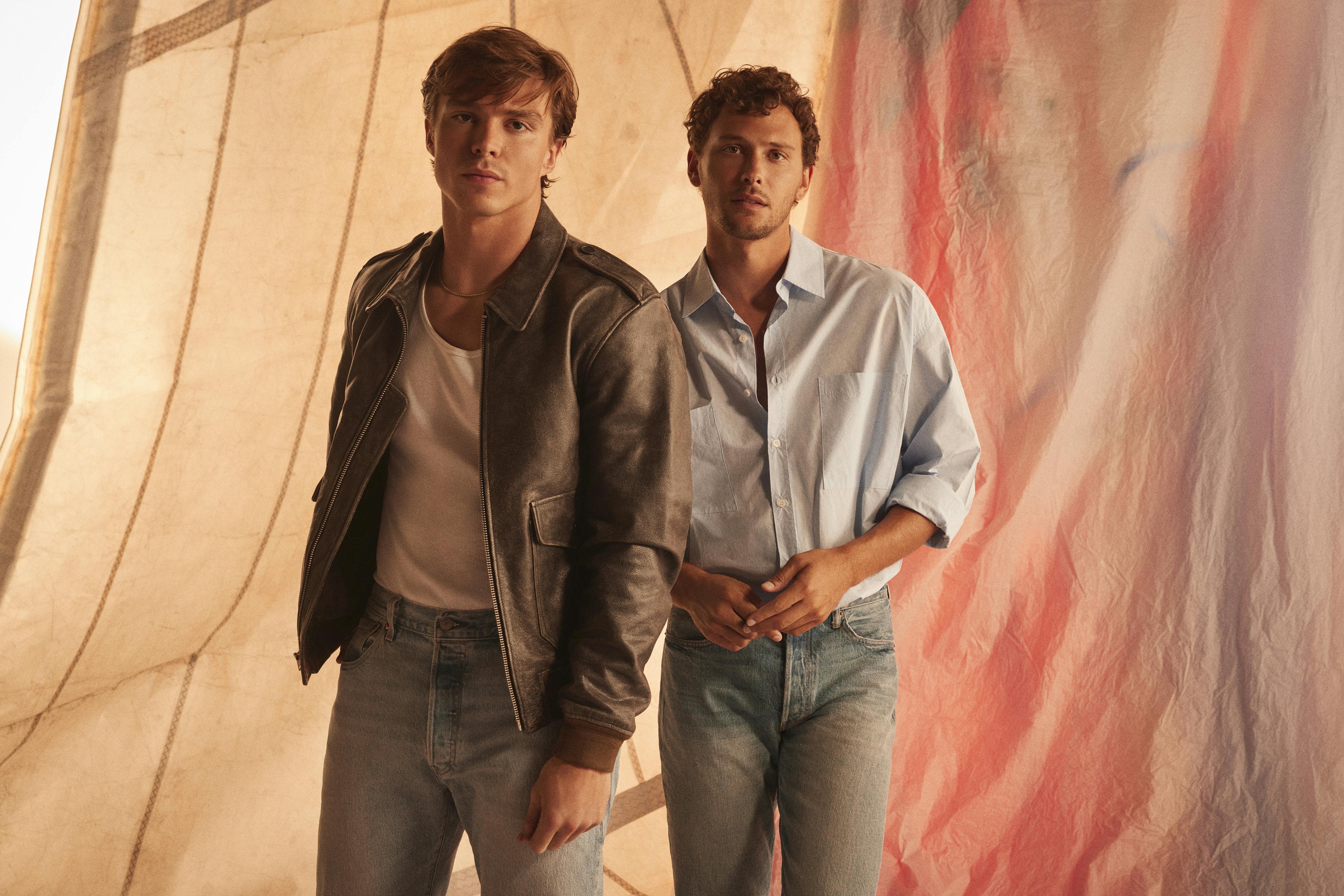 Nicholas Alexander Chavez and Cooper Koch pose against a backdrop of vintage boat sails.