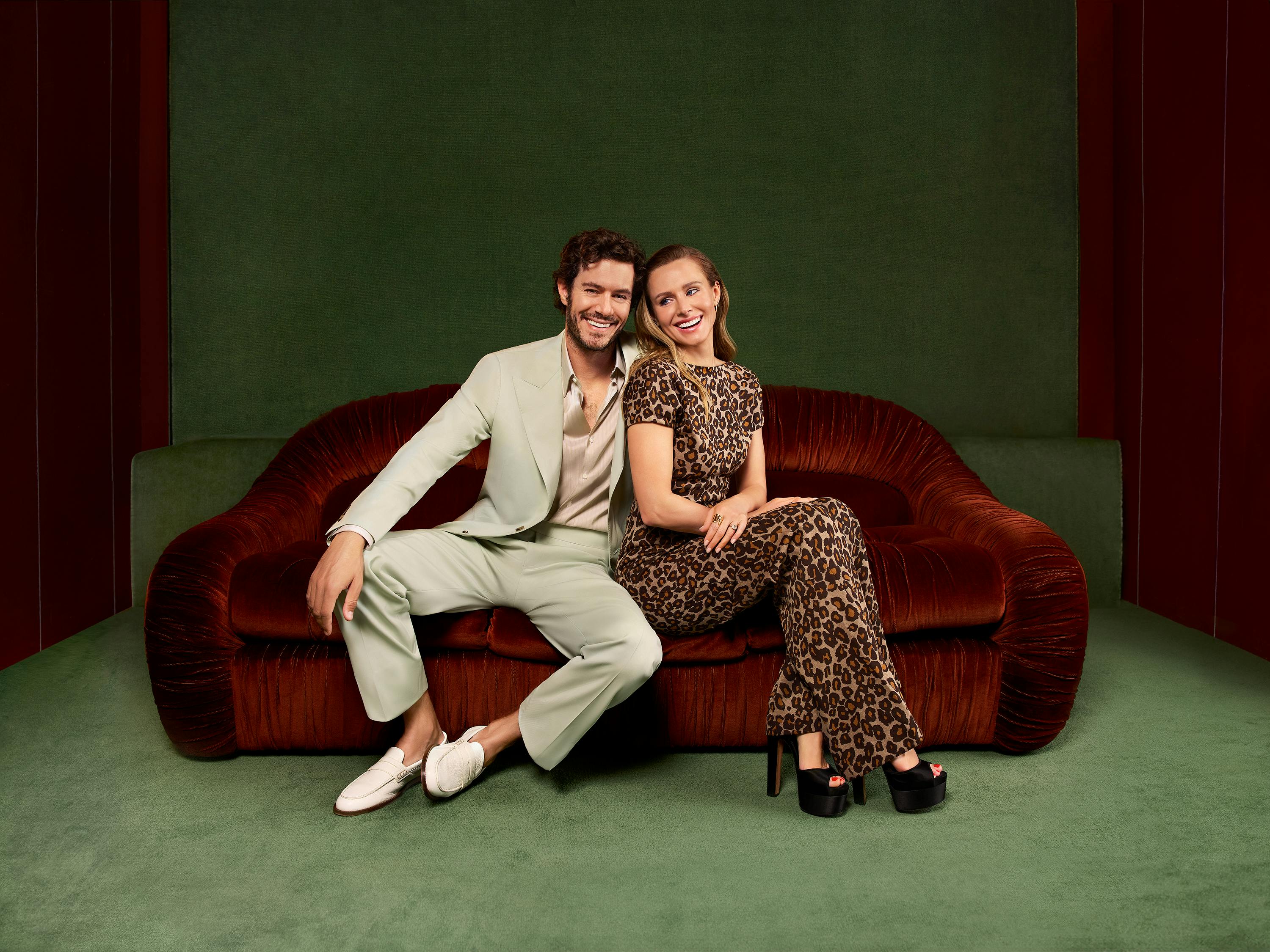 Noah (Adam Brody) and Joanne (Kristen Bell) sit on a red velvet couch in a green room.