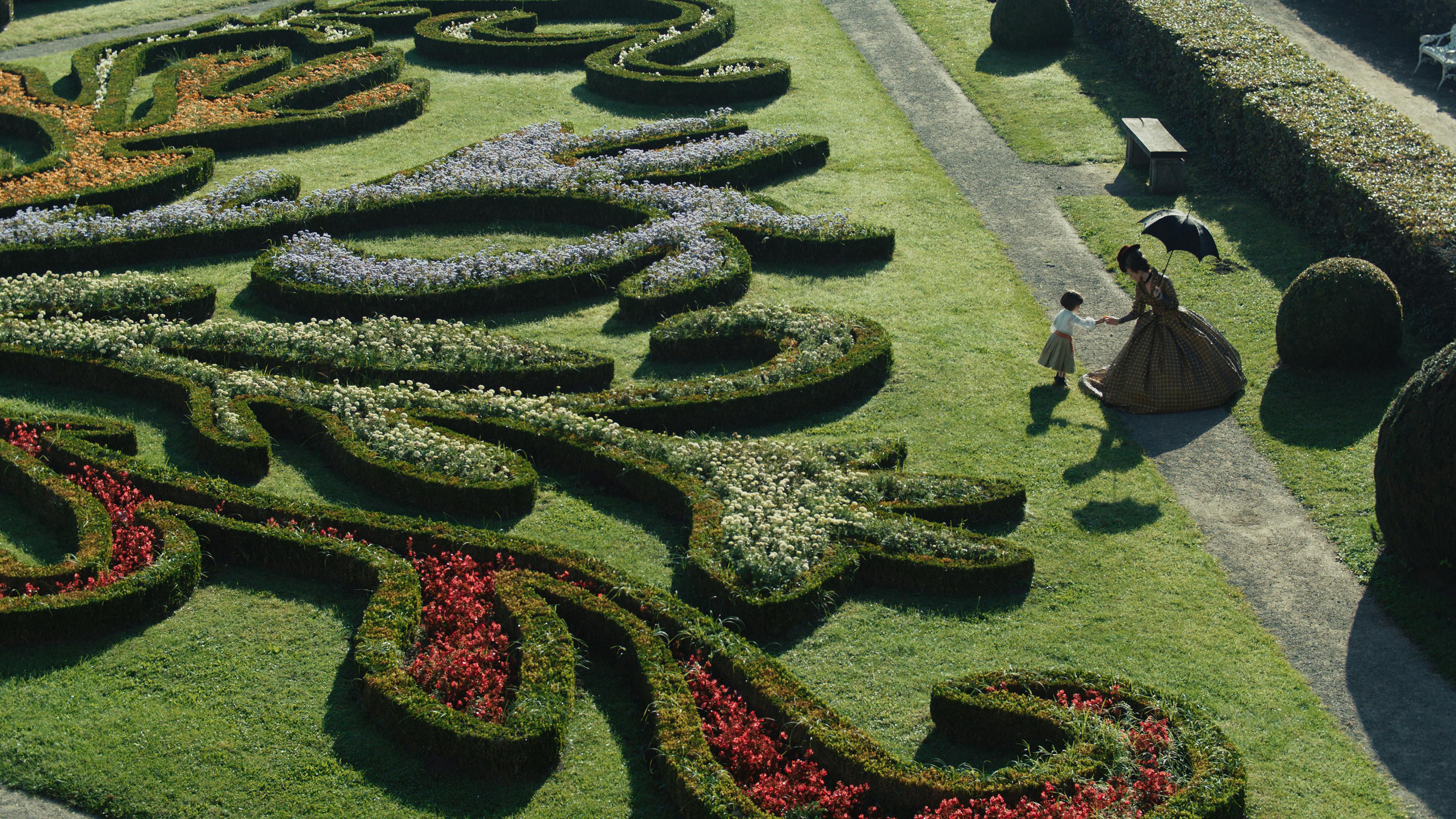 Empress Elisabeth (Devrim Lingnau) stands at an ornate, maze-like lawn.