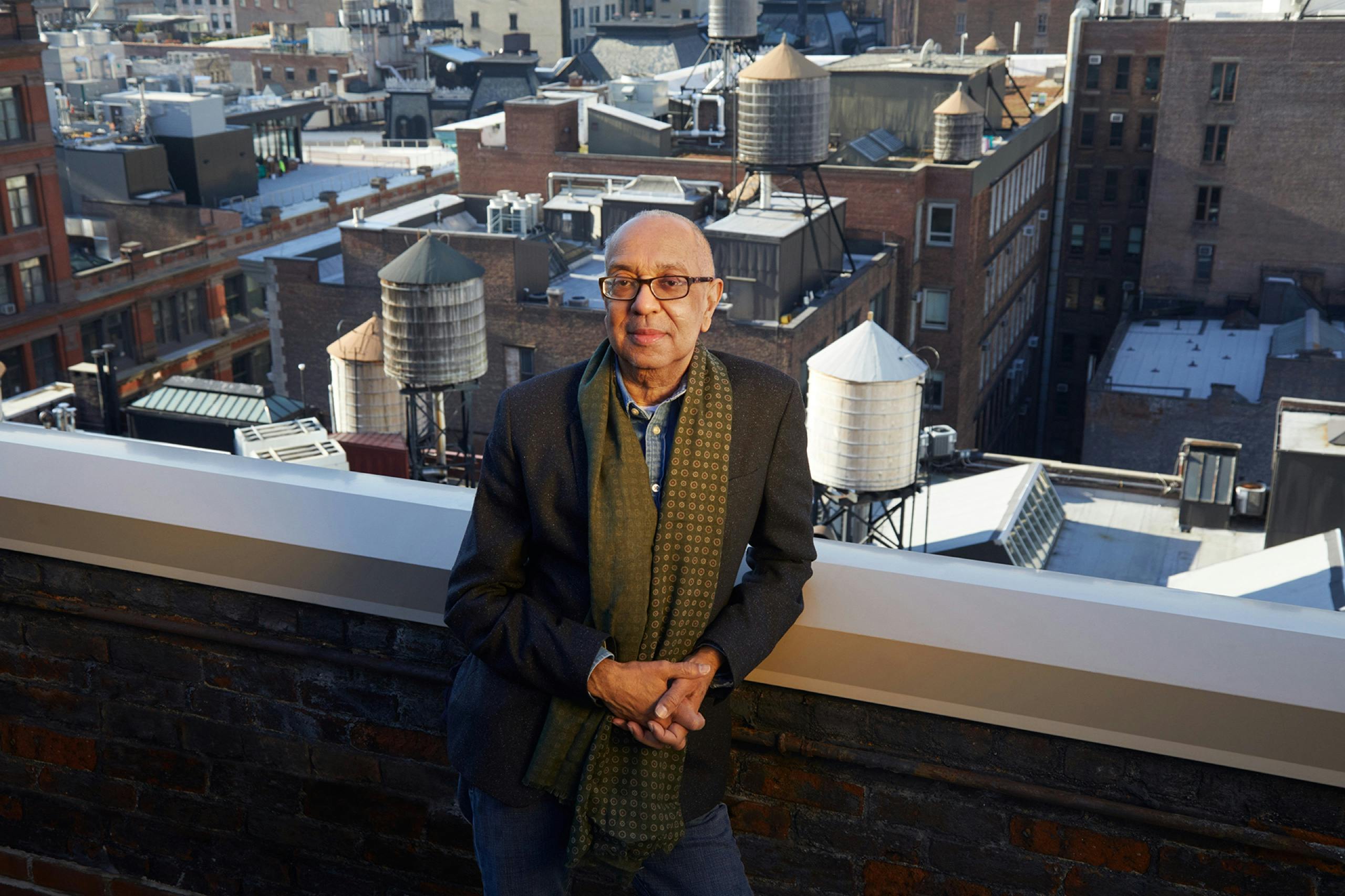 Director George C. Wolfe stands on a New York City rooftop. Behind him: a glimpse of the city.