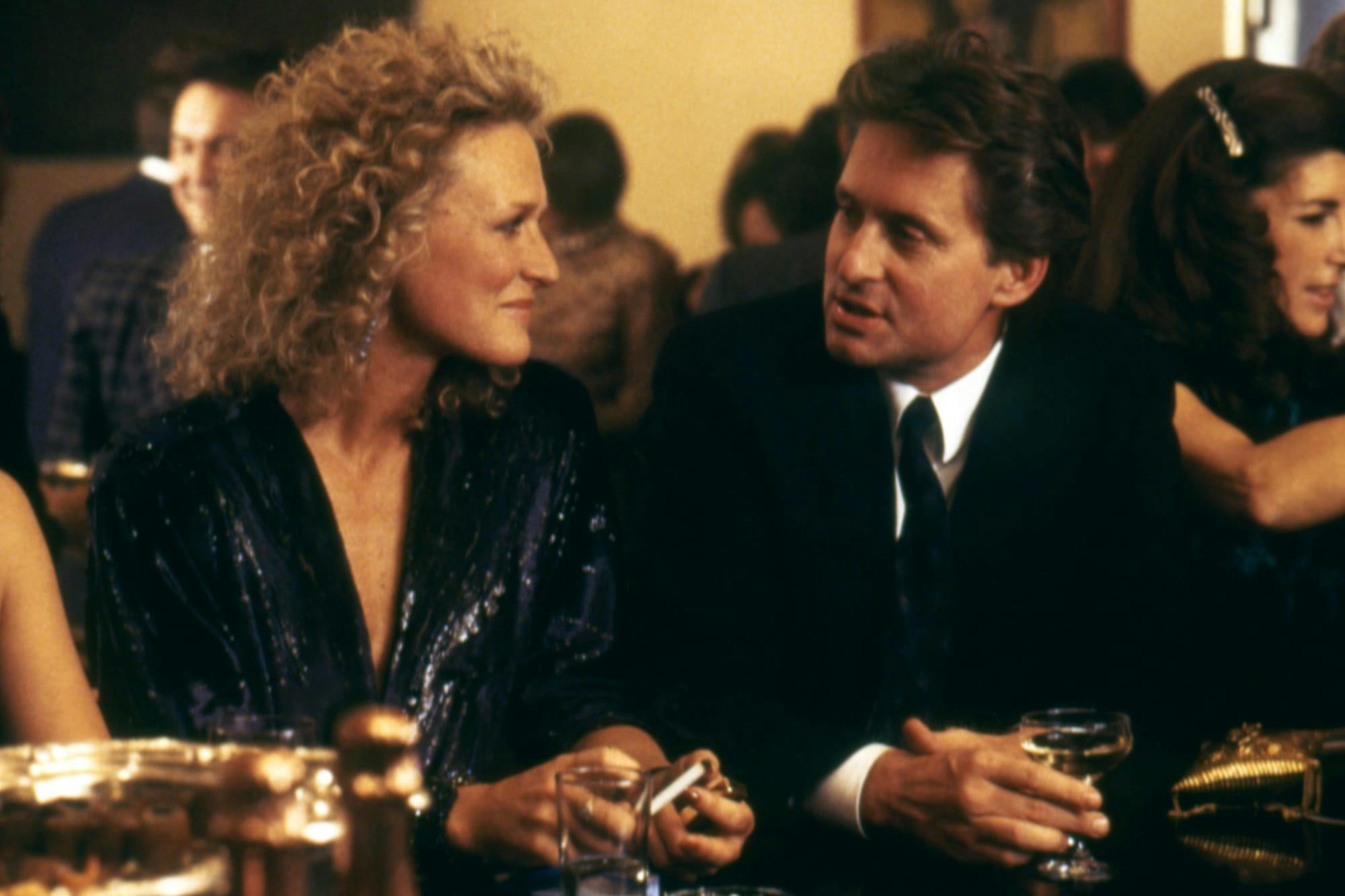 Alex Forrest (Glenn Close) and Dan Gallagher (Michael Douglas) in Fatal Attraction sit at a bar counter together drinking and talking.