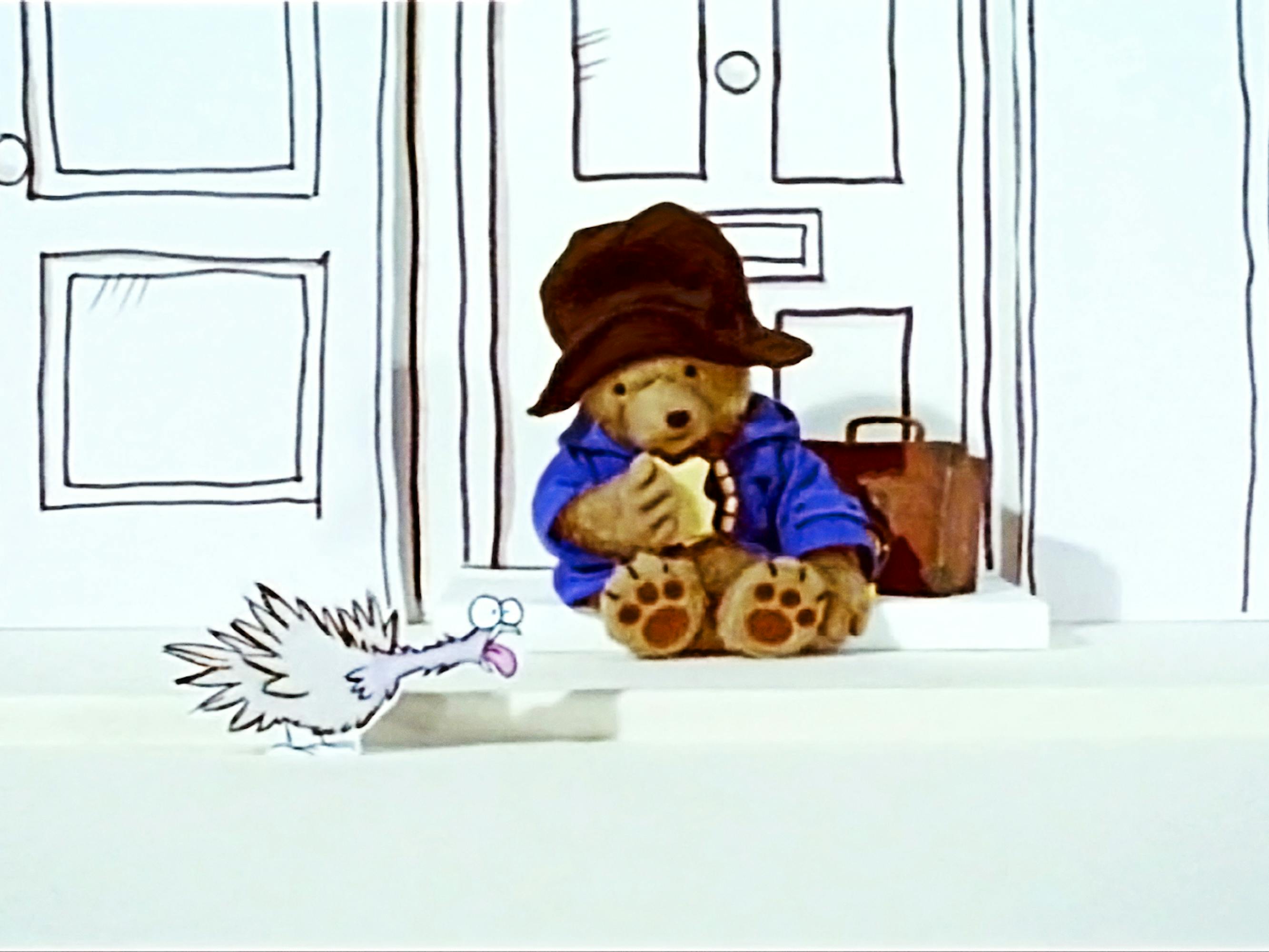 Paddington (Ben Whishaw) looks slightly dejected sitting on a stoop eating some marmalade toast.