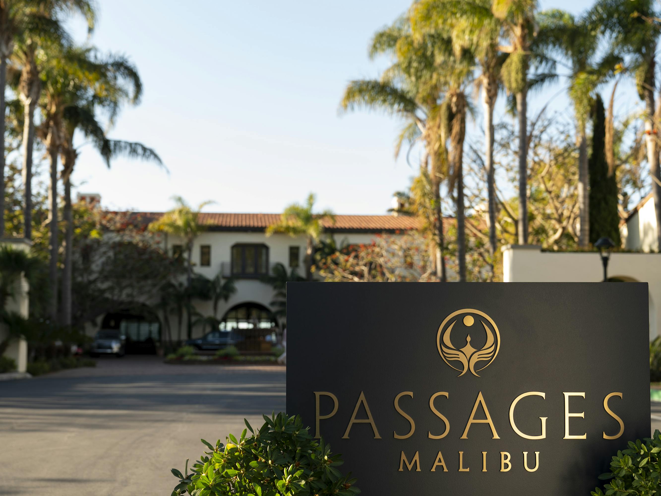 Passages Rehab center in Malibu. The parking lot is empty, and flanked by tall palm trees.