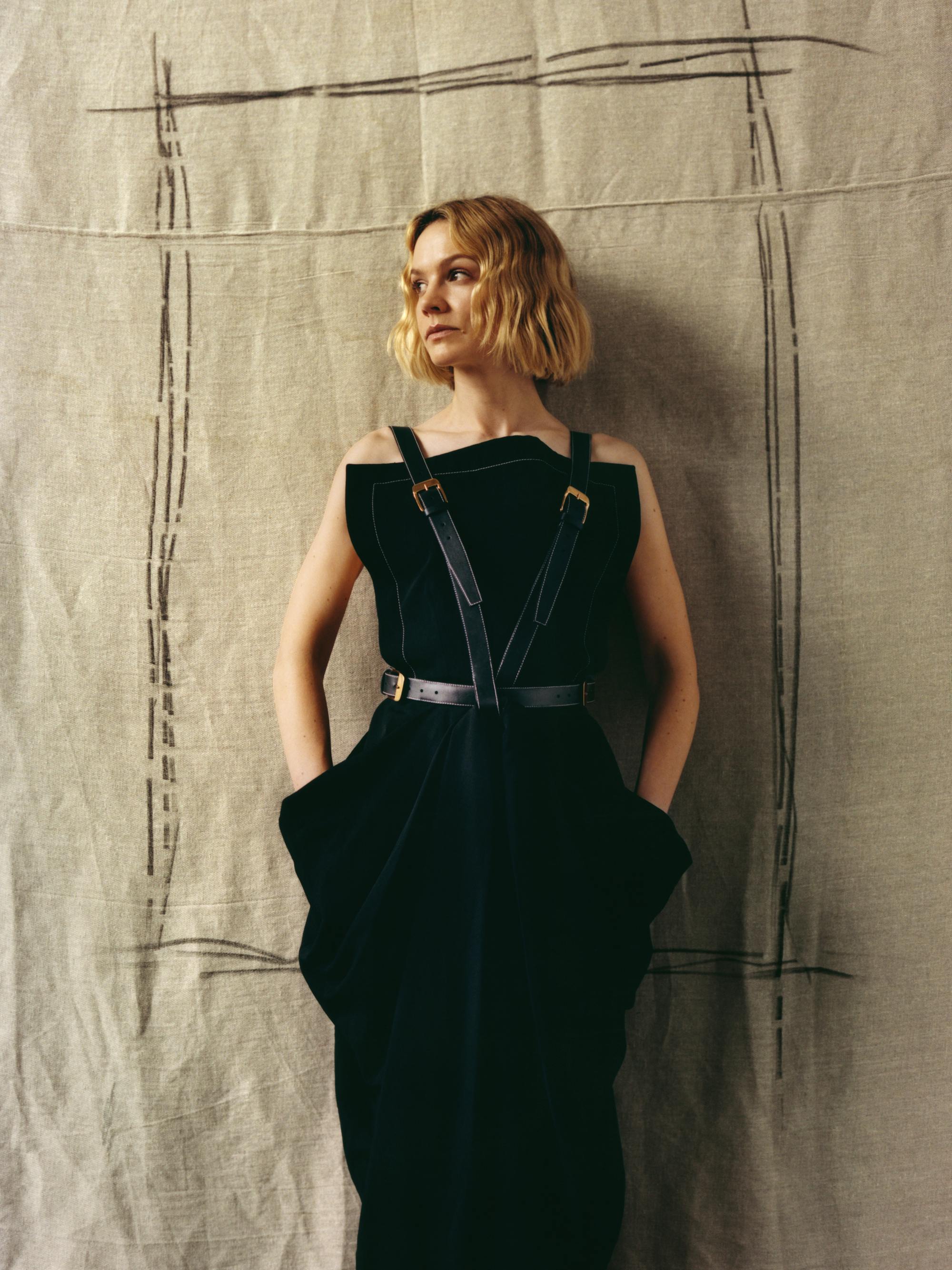 Carey Mulligan wears a black outfit with strappy suspenders.