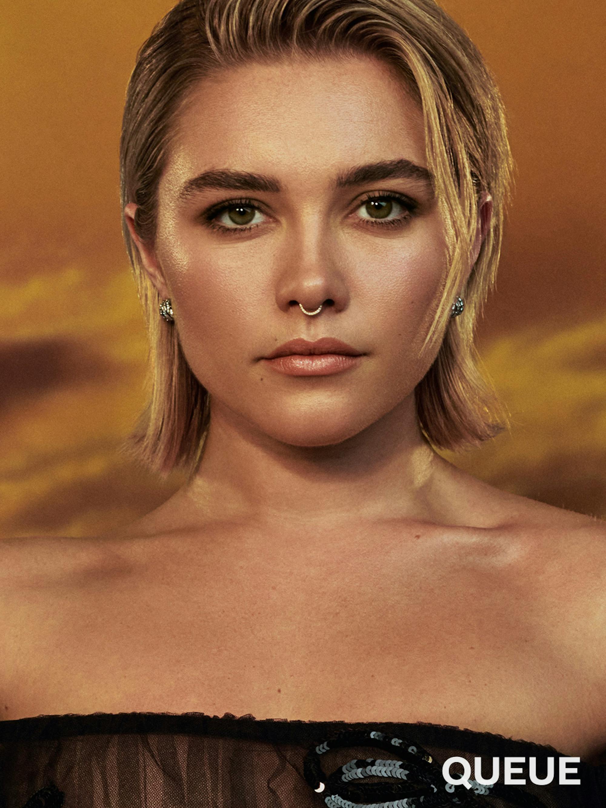 Florence Pugh wears a black sequin sheer dress, nose ring, and earrings.