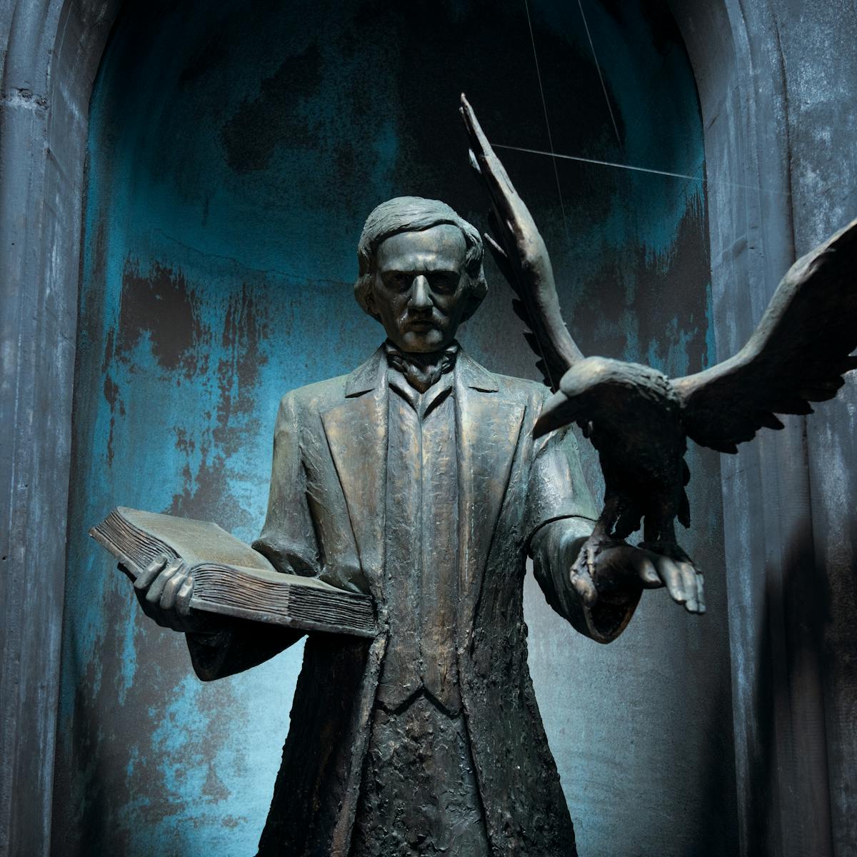A statue at Nevermore — presumably of Edgar Allen Poe, because of the raven on his arm — holds a book and looks ominous. 