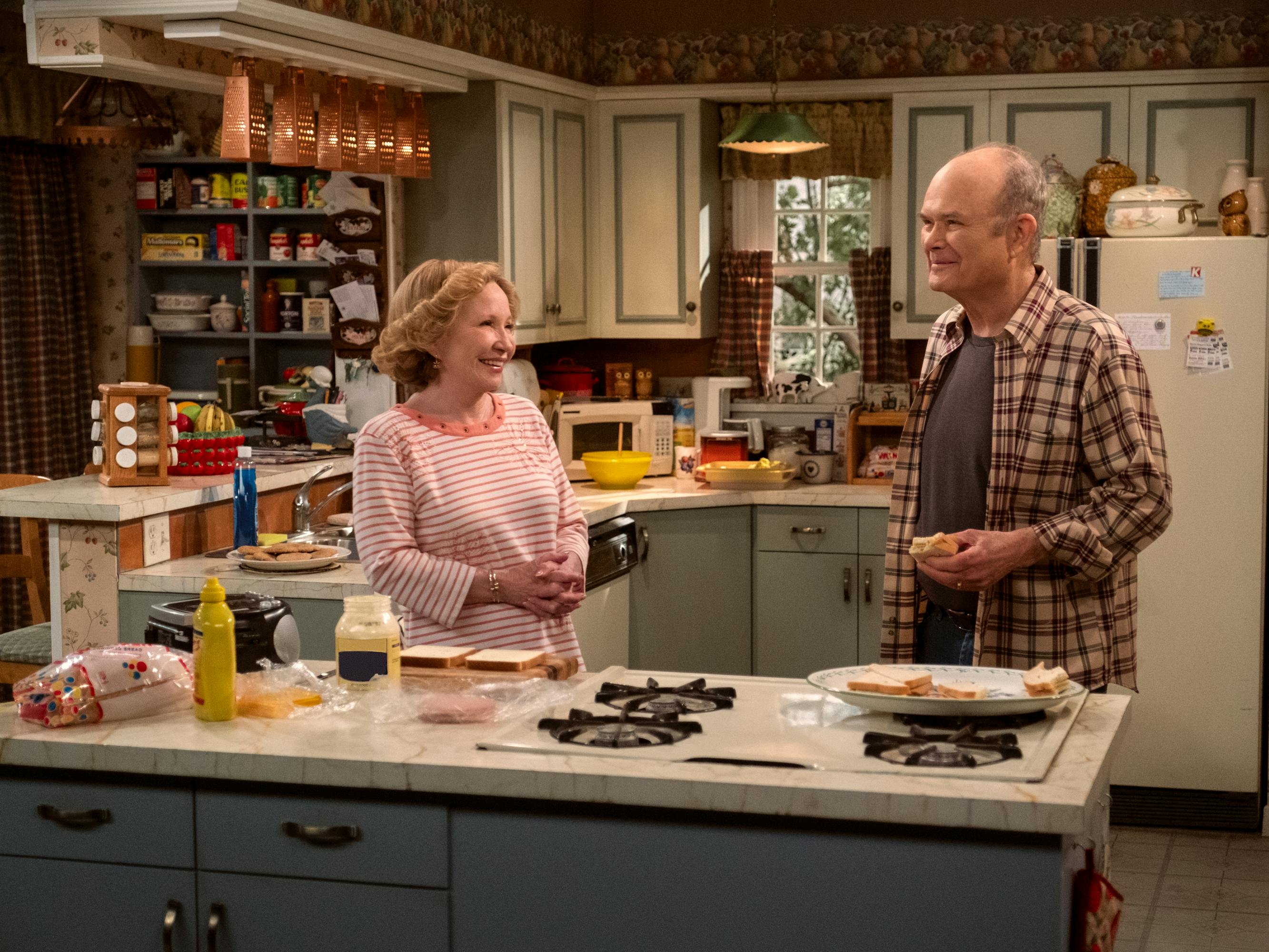 Kitty Forman (Debra Jo Rupp) and Red Forman (Kurtwood Smith) stand together in the kitchen making a sandwich.