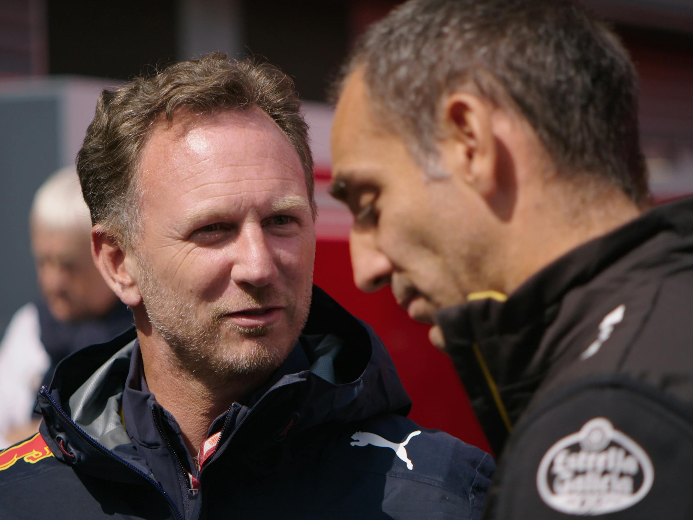 Christian Horner on the left looks over to Cyril Abiteboul who is in profile in the foreground.
