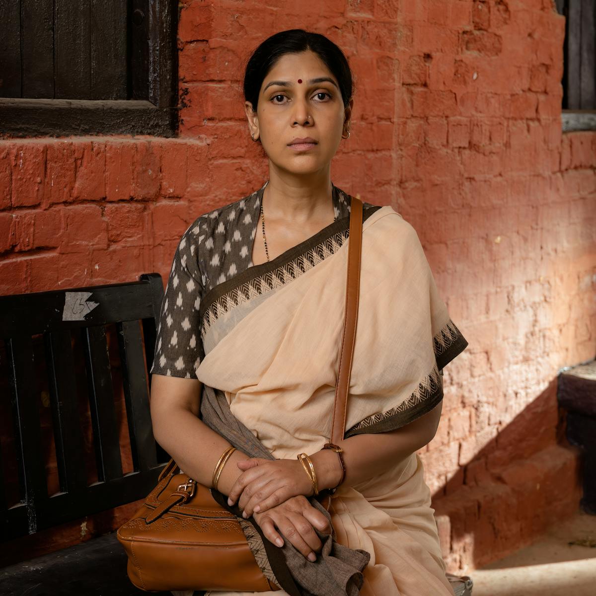 Sakshi Tanwar looks directly at the camera. behind her is a brick wall.