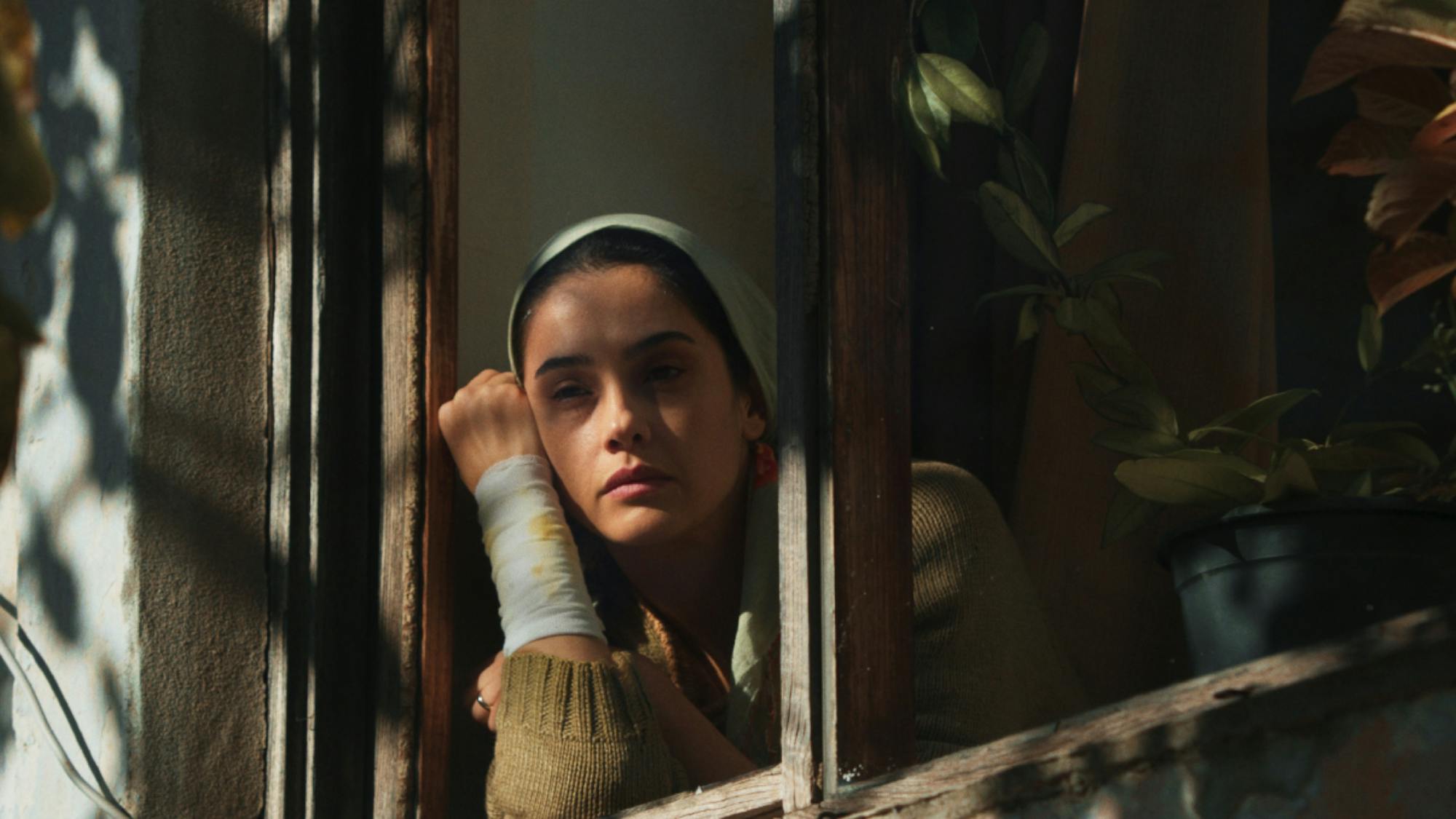 Ruhiye looks out from her window, arm bandaged.