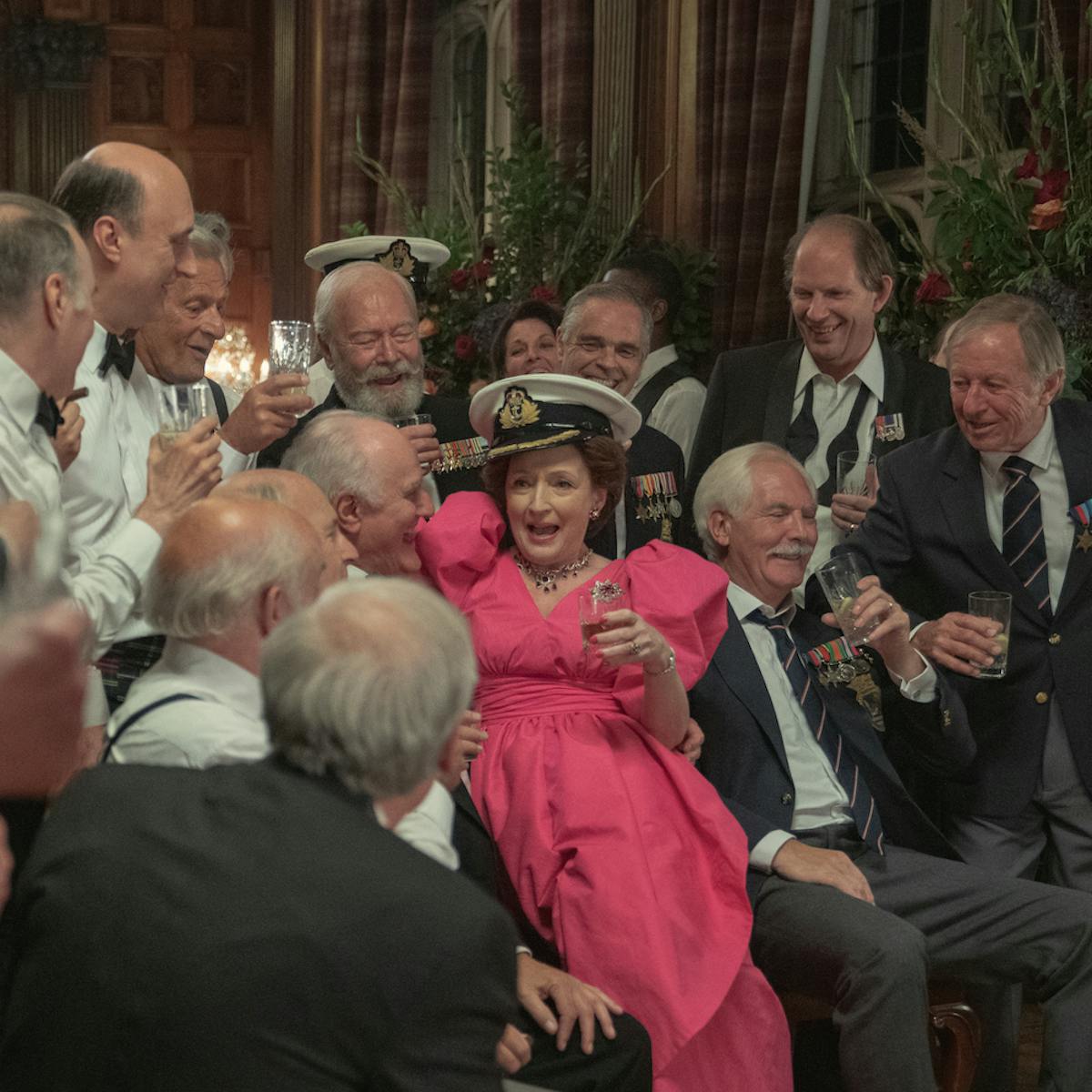Princess Margaret (Lesley Manville) wears a fantastic pink dress and flirts with a crowd of men in suits.