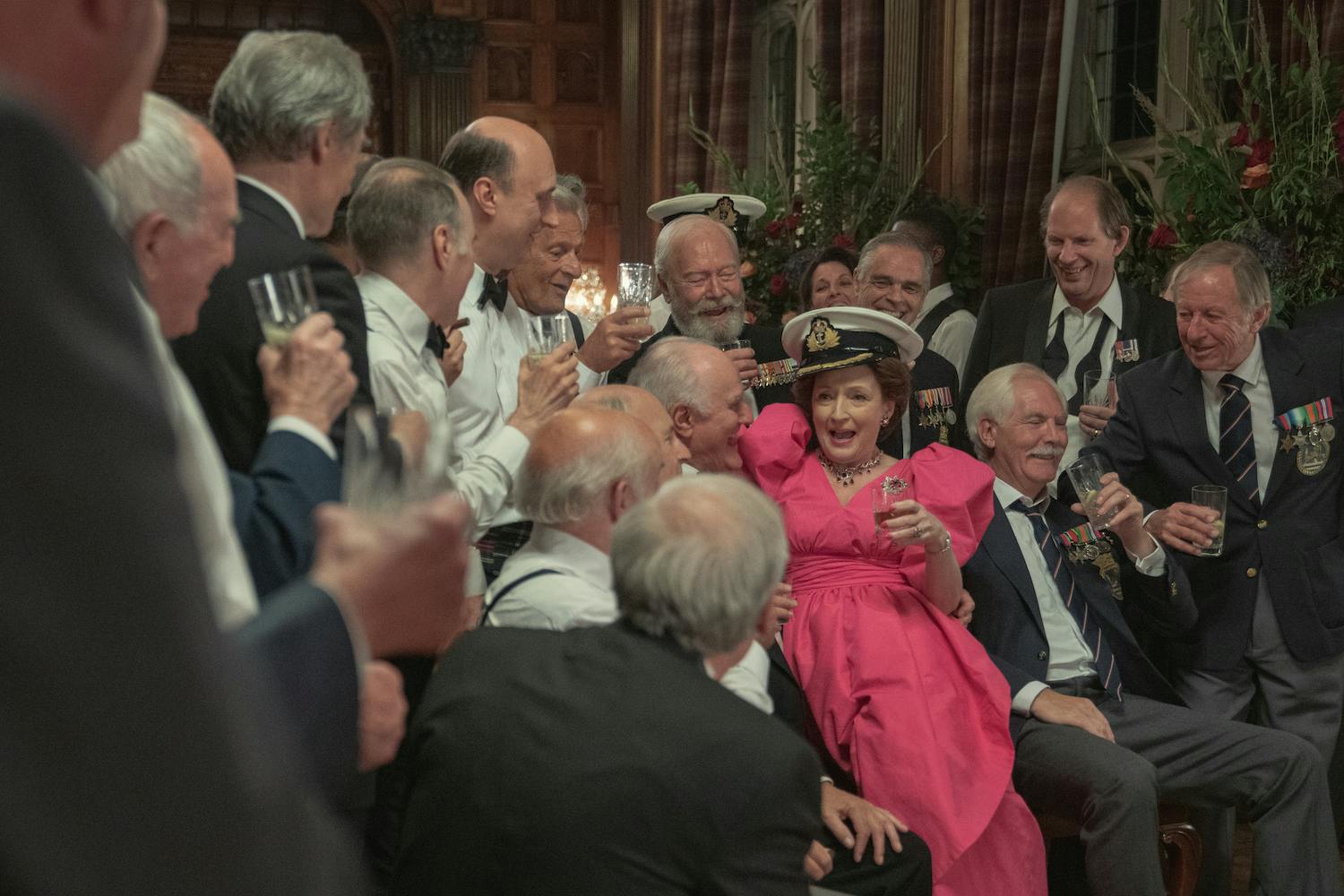 Princess Margaret (Lesley Manville) wears a fantastic pink dress and flirts with a crowd of men in suits.