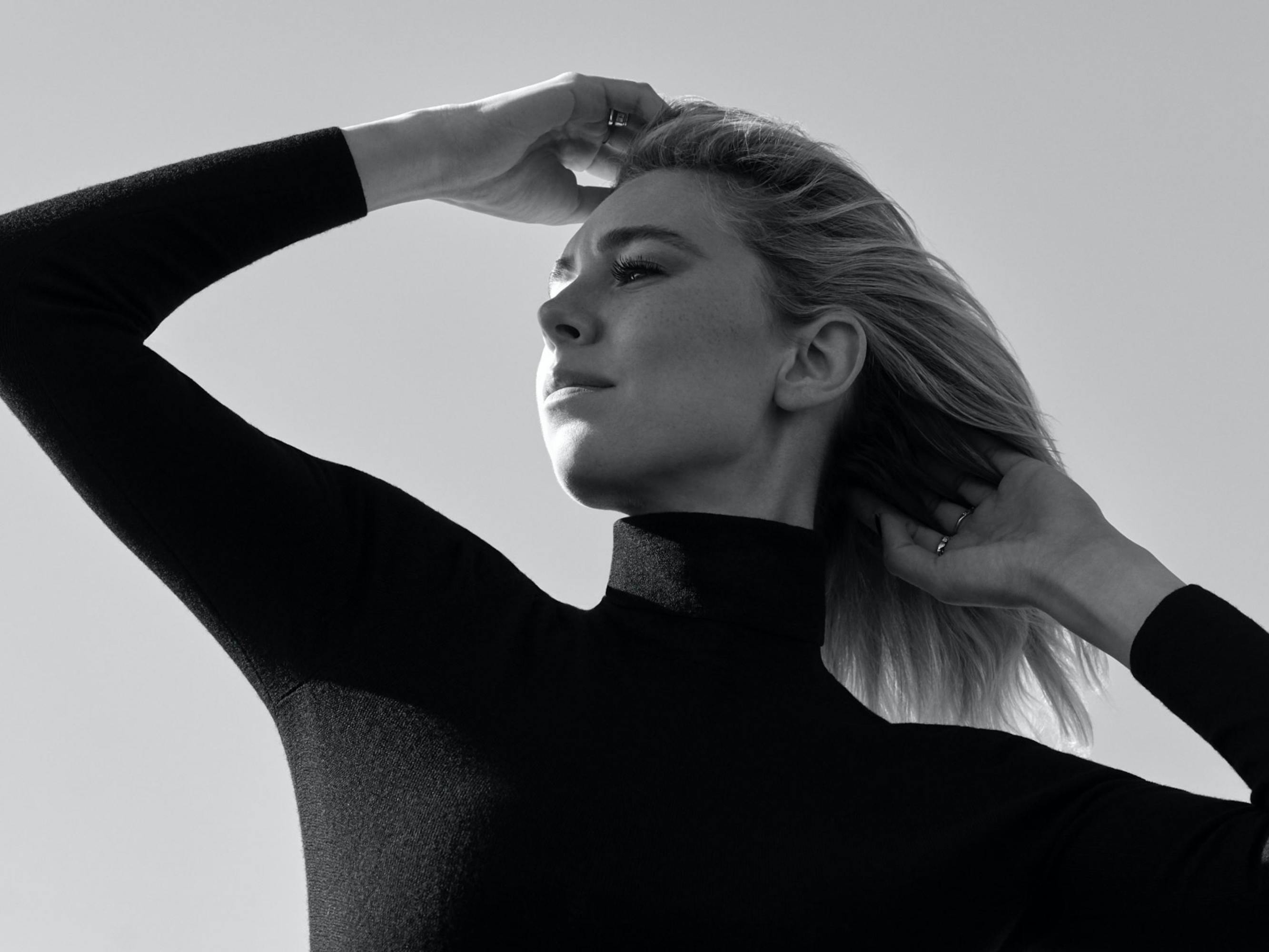 Vanessa Kirby poses in profile, arms akimbo. The sun hits her face and her hair blows in the breeze.