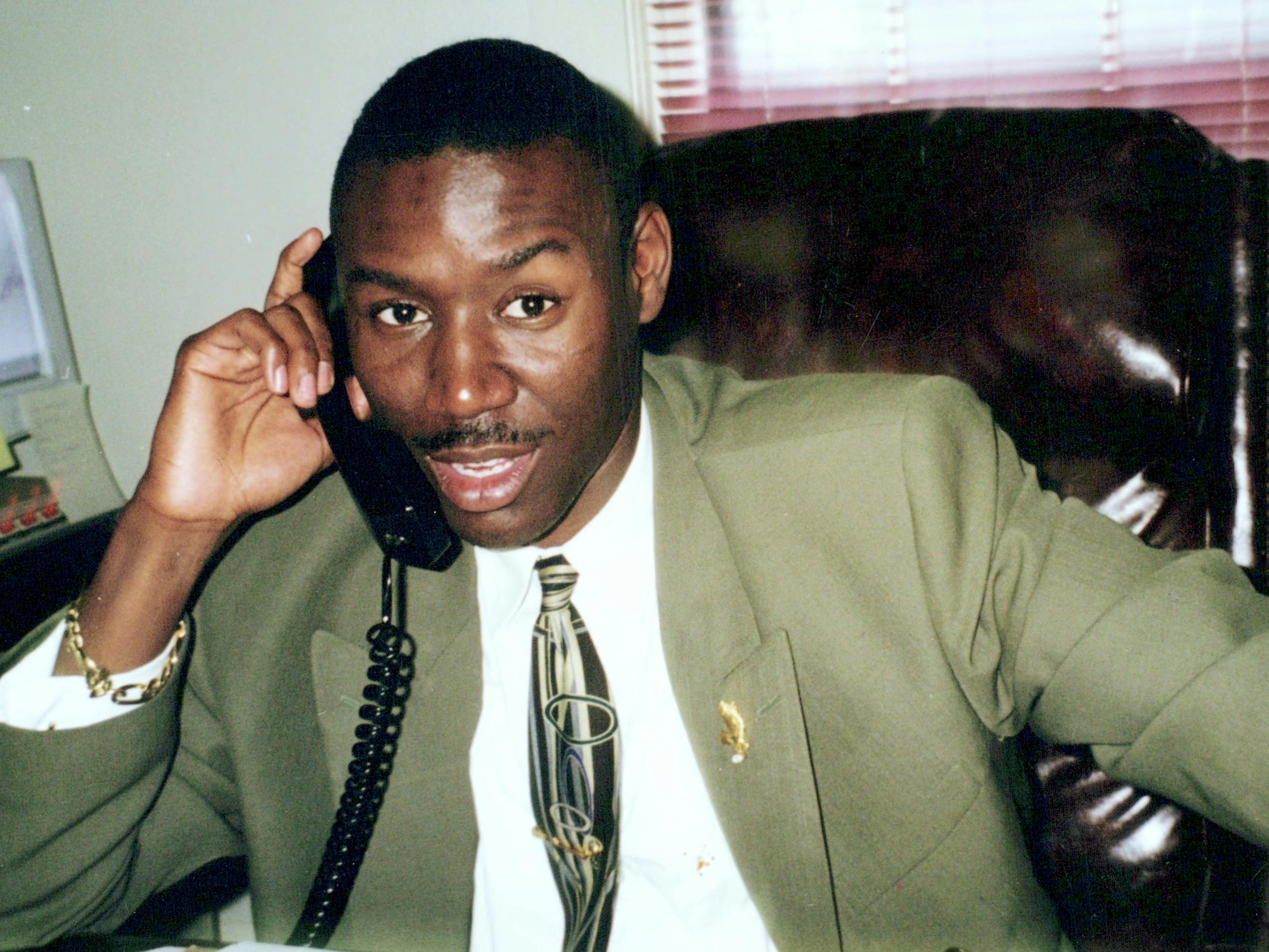 A young Ben Crump wears a green blazer and tie and looks suave!