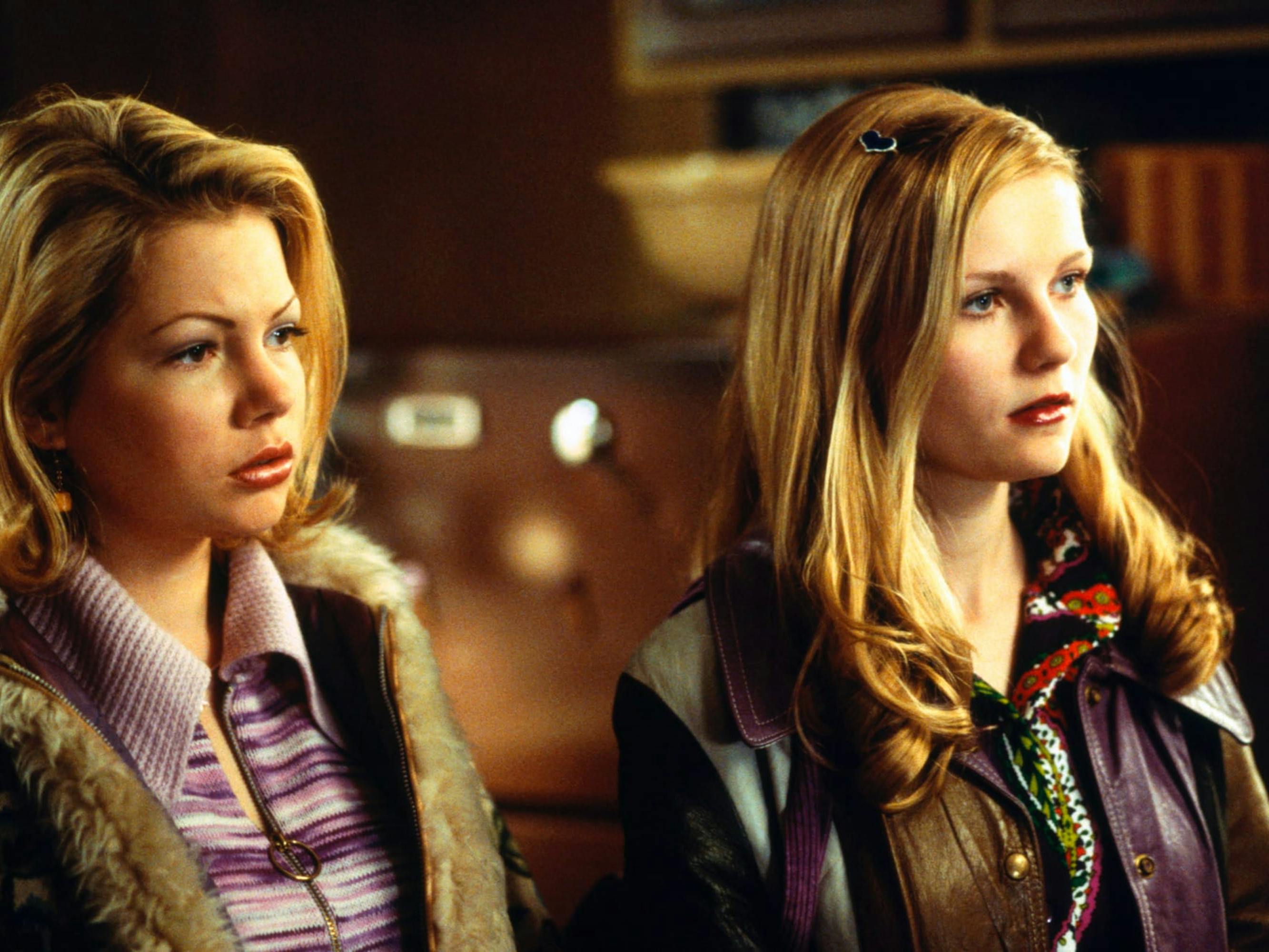 Ariene Lorenzo (Michelle Williams) and Betsy Jobs (Kirsten Dunst) wear purple and brown sweaters and jackets.