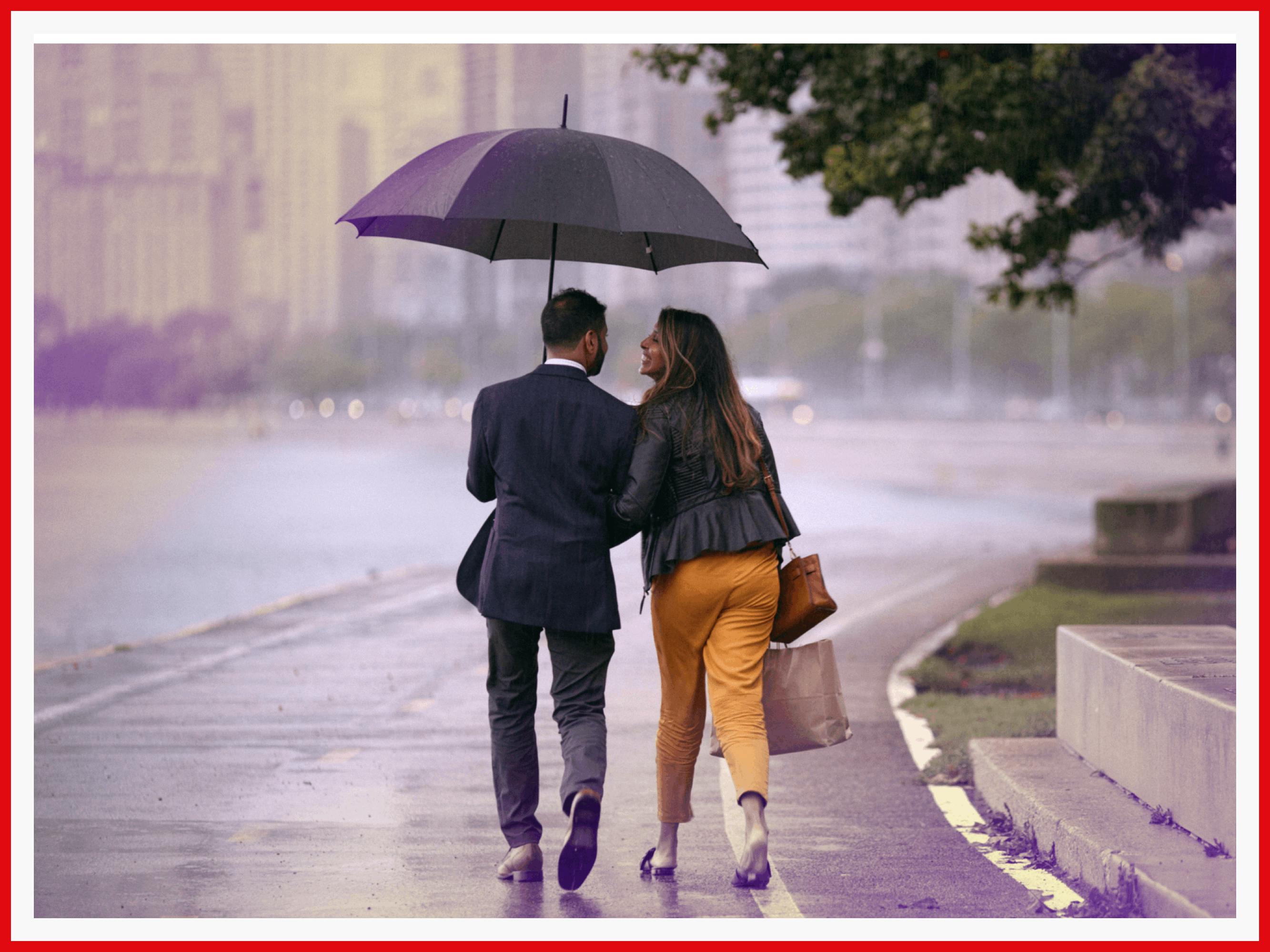 The couple walk down a rainy street.