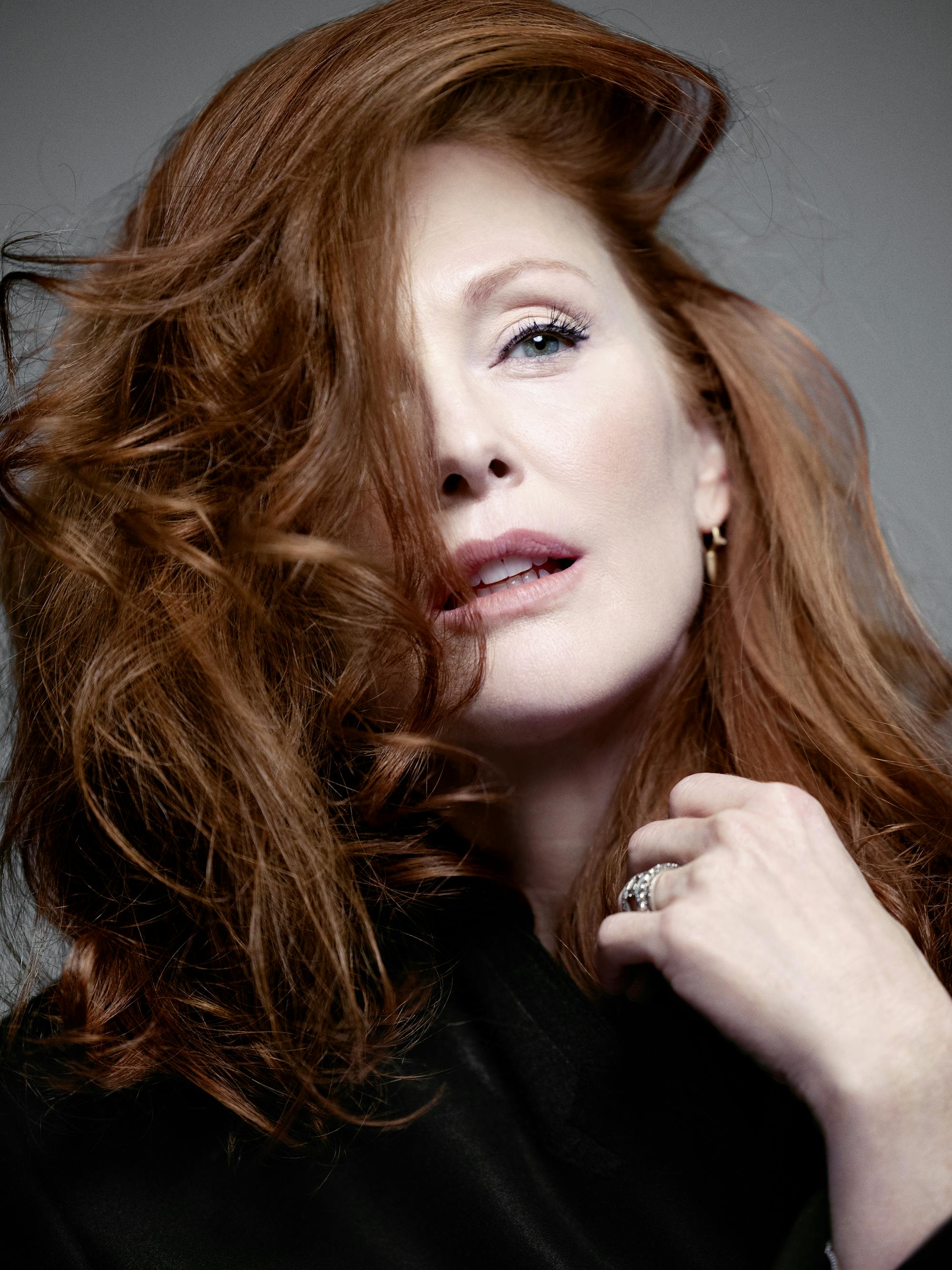 Julianne Moore wears a black ensemble and adjusts her red hair.