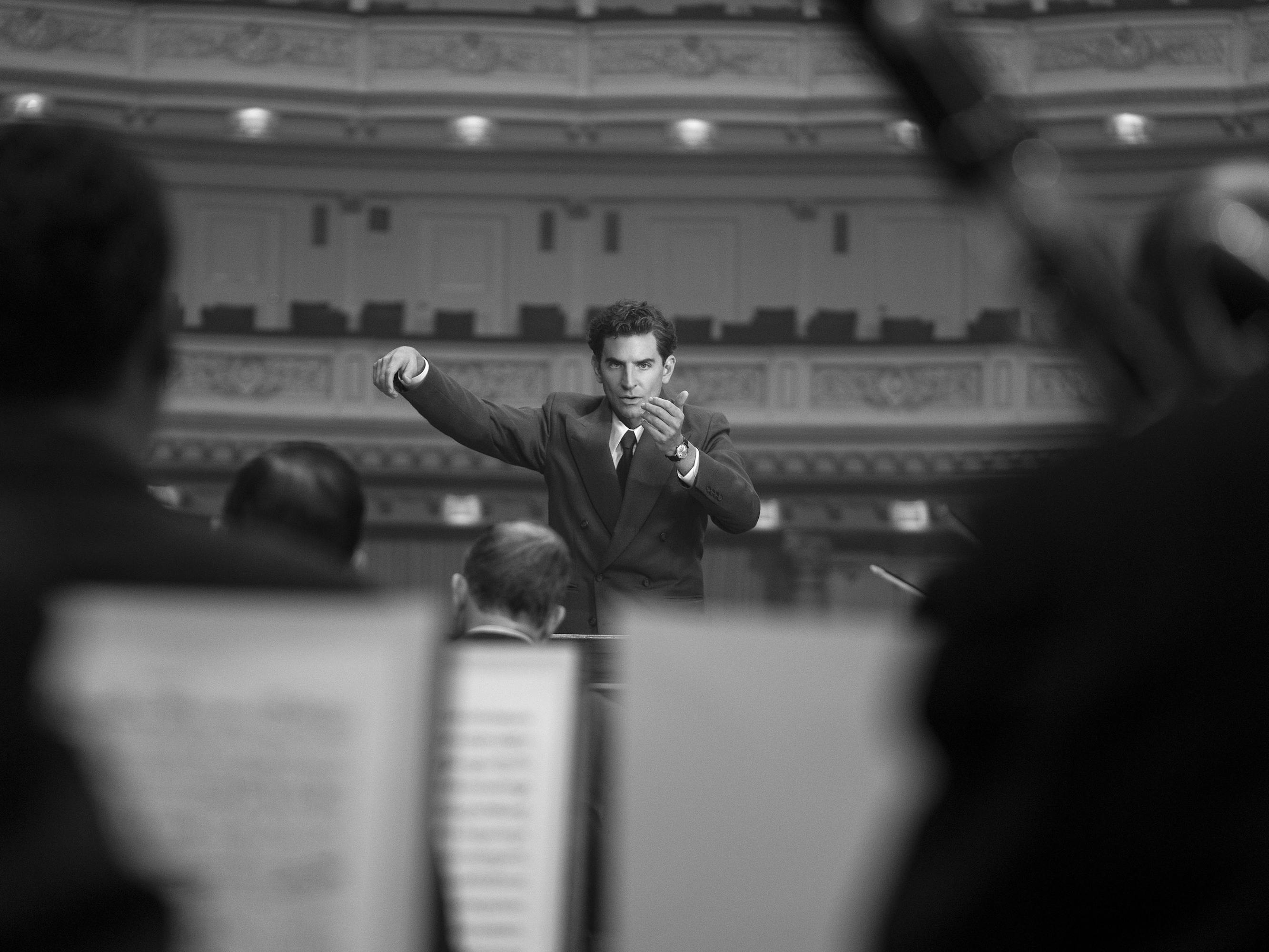 Leonard Bernstein (Bradley Cooper) conducts an orchestra with an intense expression on his face. 