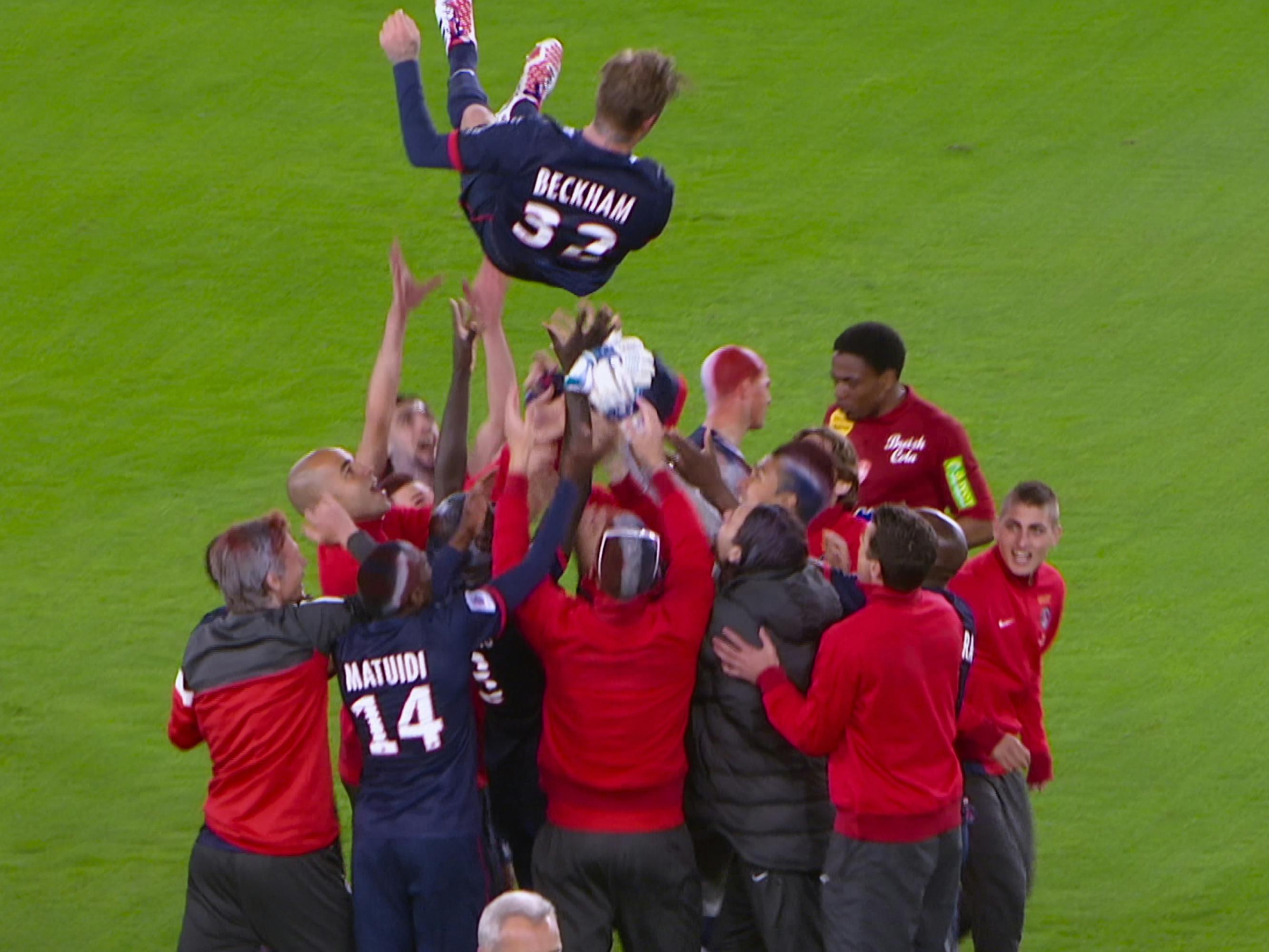 David Beckham gets thrown into the air by some teammates wearing red, black, and navy.