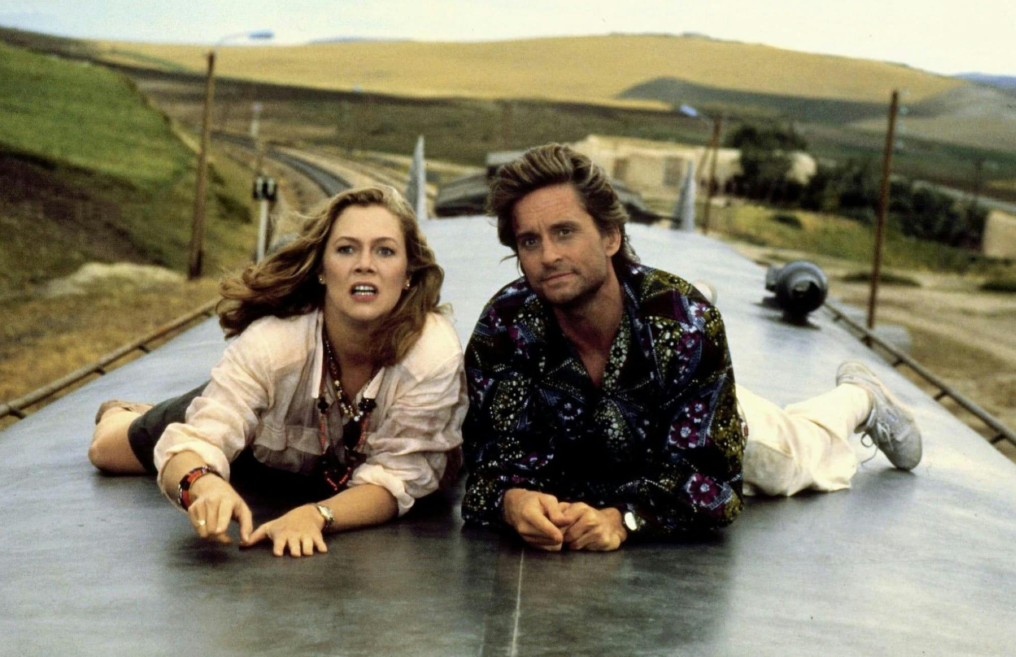 Joan Wilder (Kathleen Turner) and Jack T. Colton (Michael Douglas) in The Jewel of the Nile lie on the top of a train. 