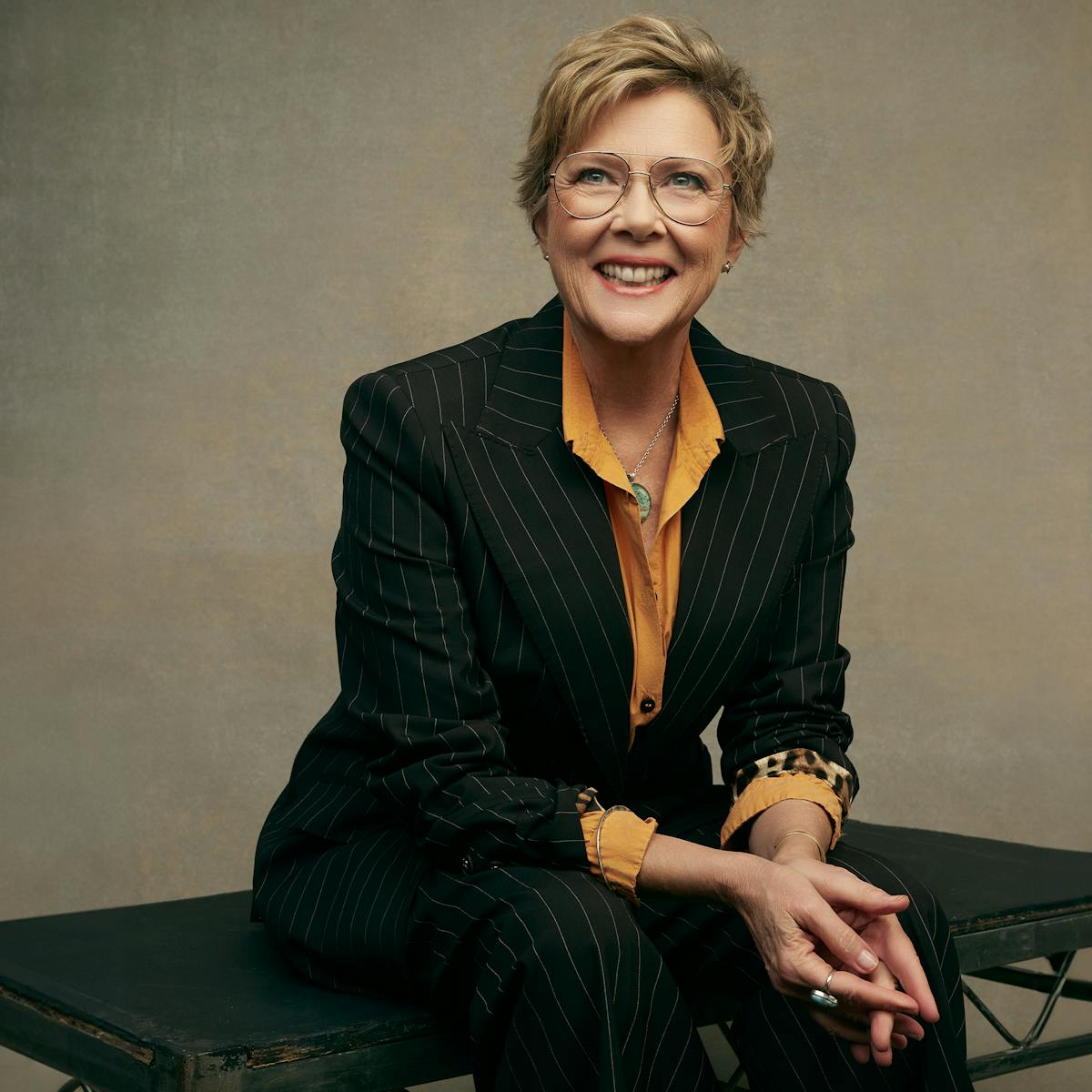 Annette Bening wears a black suit and a yellow shirt.