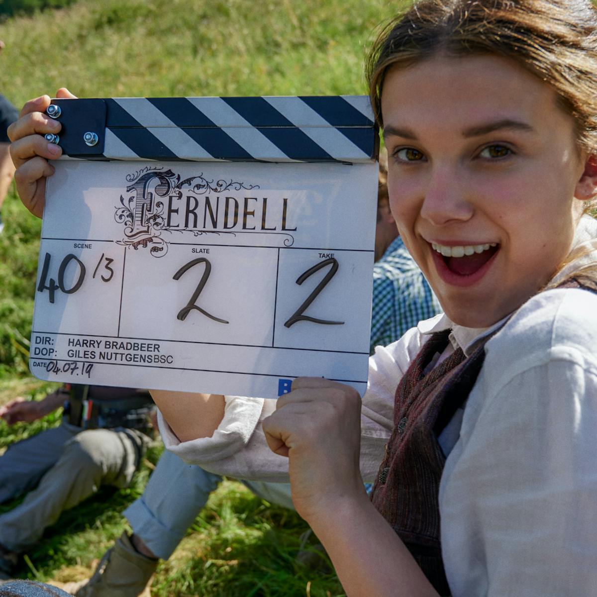 Millie Bobby Brown on set, holding a film clapper board.