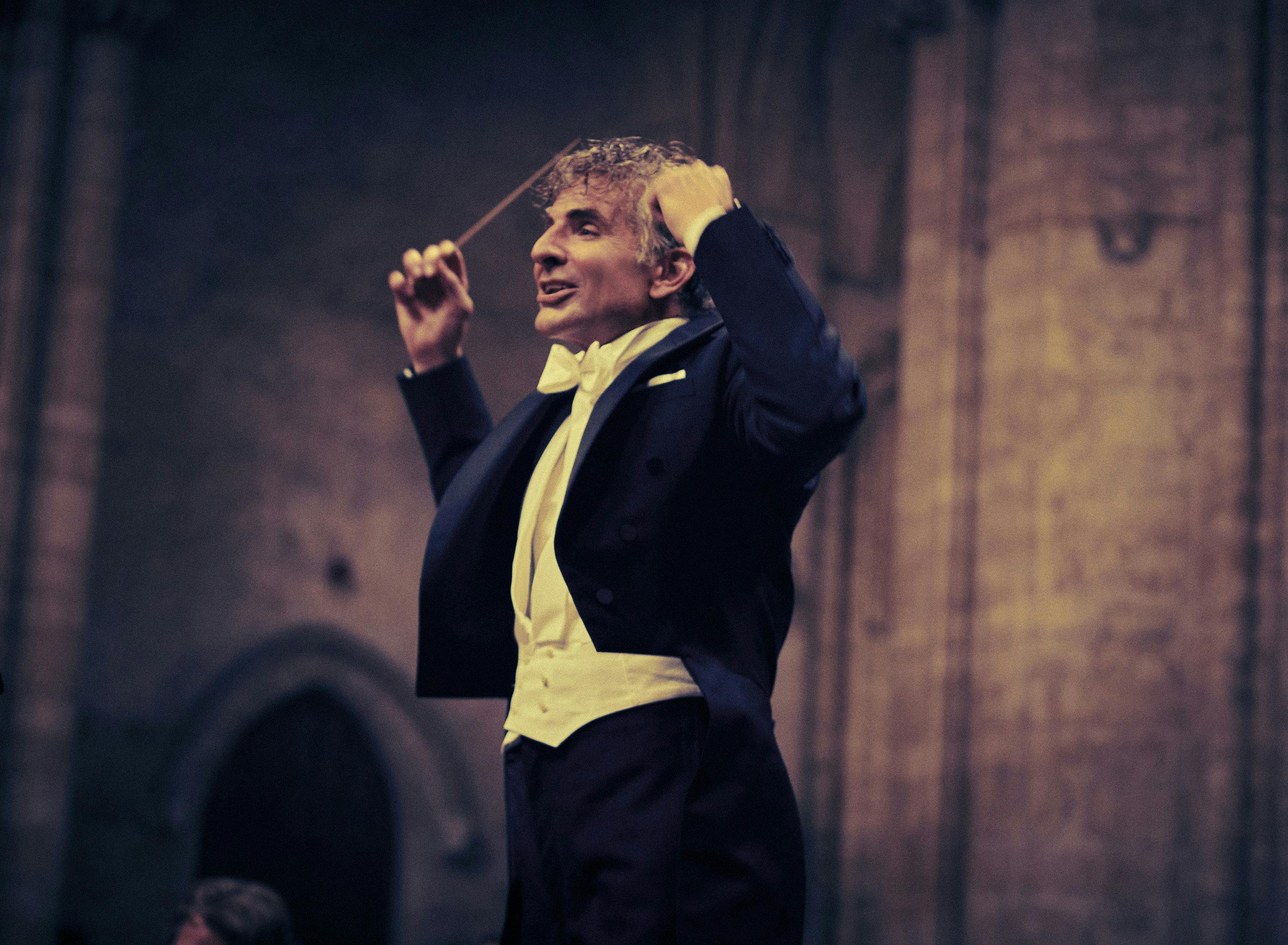 Leonard Bernstein (Bradley Cooper) conducts an orchestra.