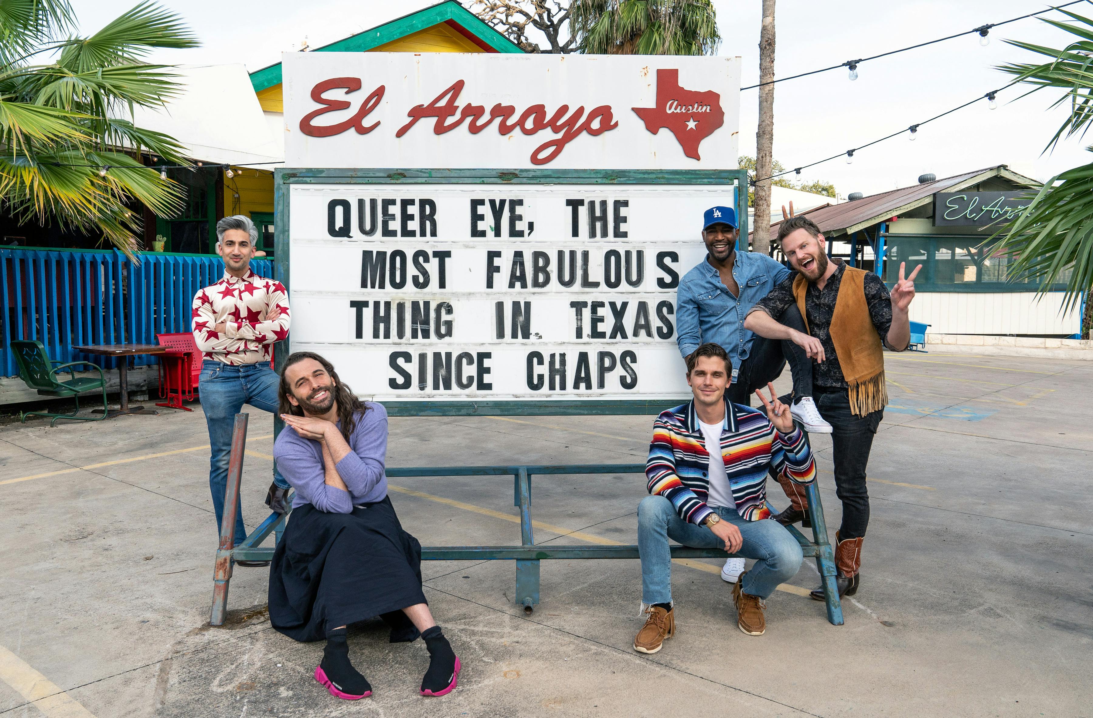 The Fab Five frame a sign that reads "Queer Eye, the most fabulous thing in texas since chaps."