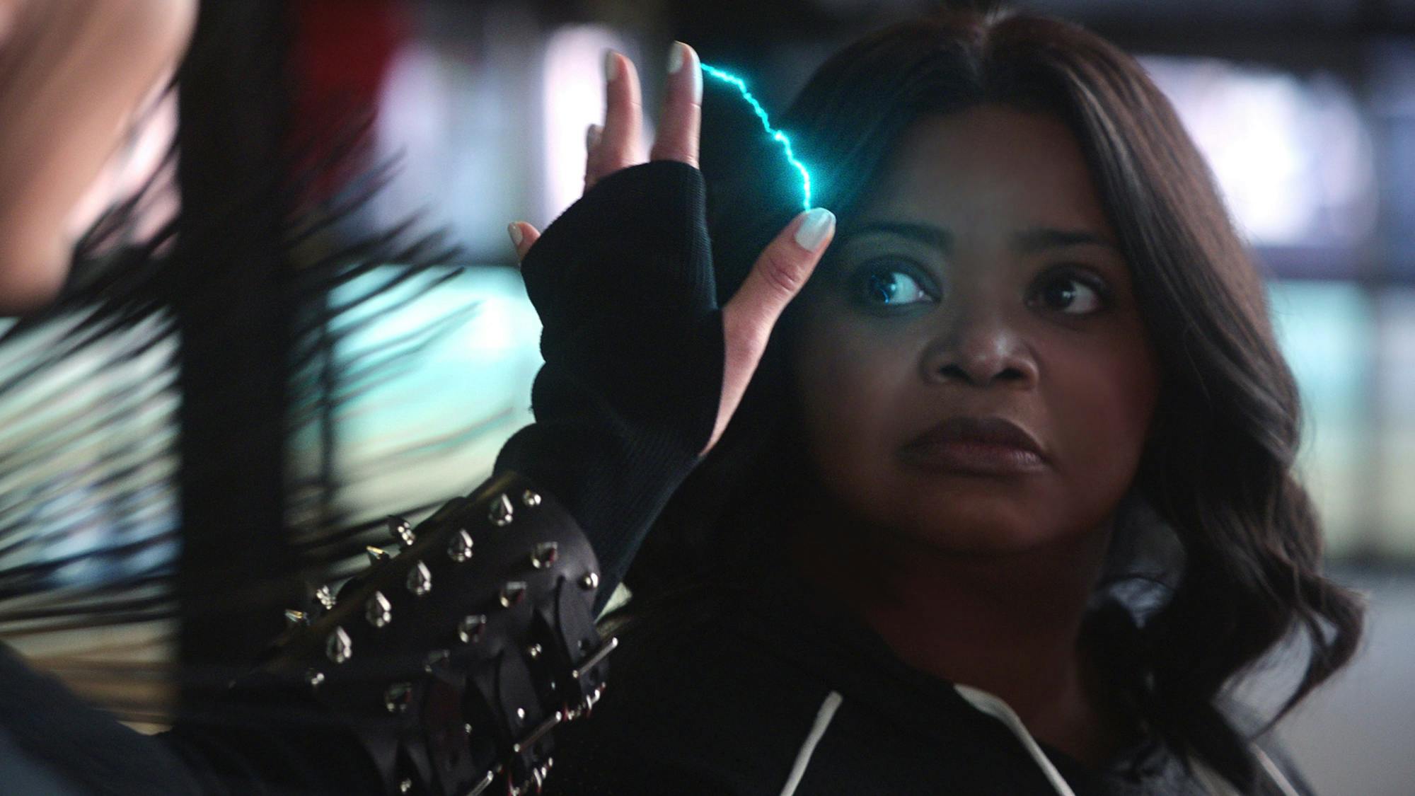 Octavia Spencer looks into a mirror as a bolt of lightning flashes between her fingers. She wears a studded cuff and appears serious. 