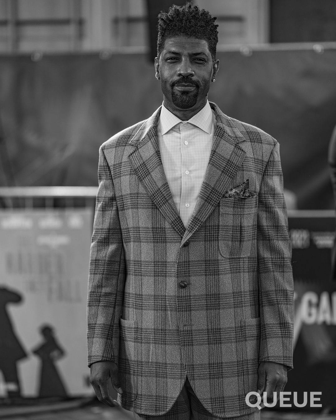 Deon Cole in a checked suit on the red carpet