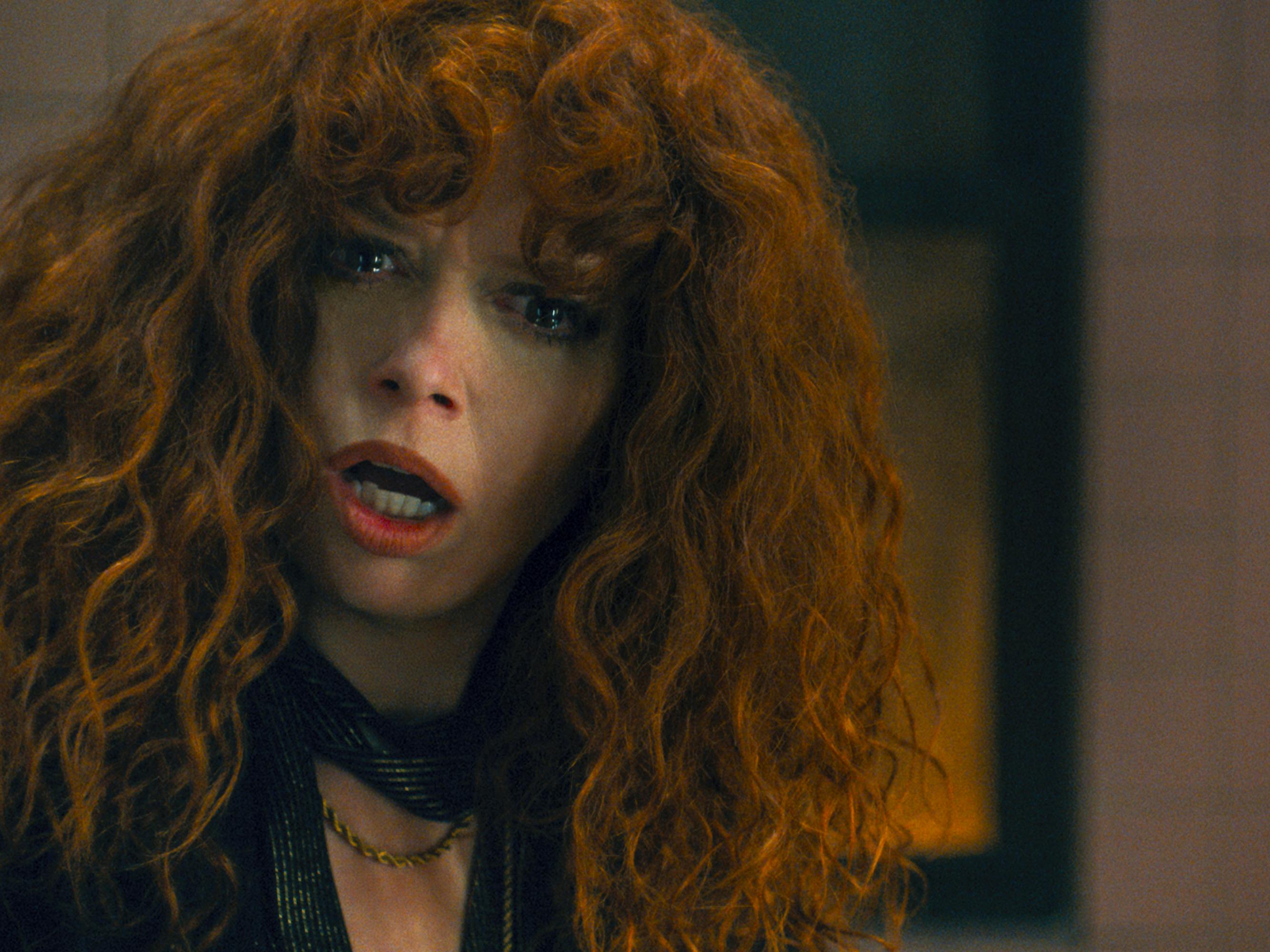 Nadia Vulvokov (Natasha Lyonne) wears a dark top and looks disoriented with her iconic head of red hair.