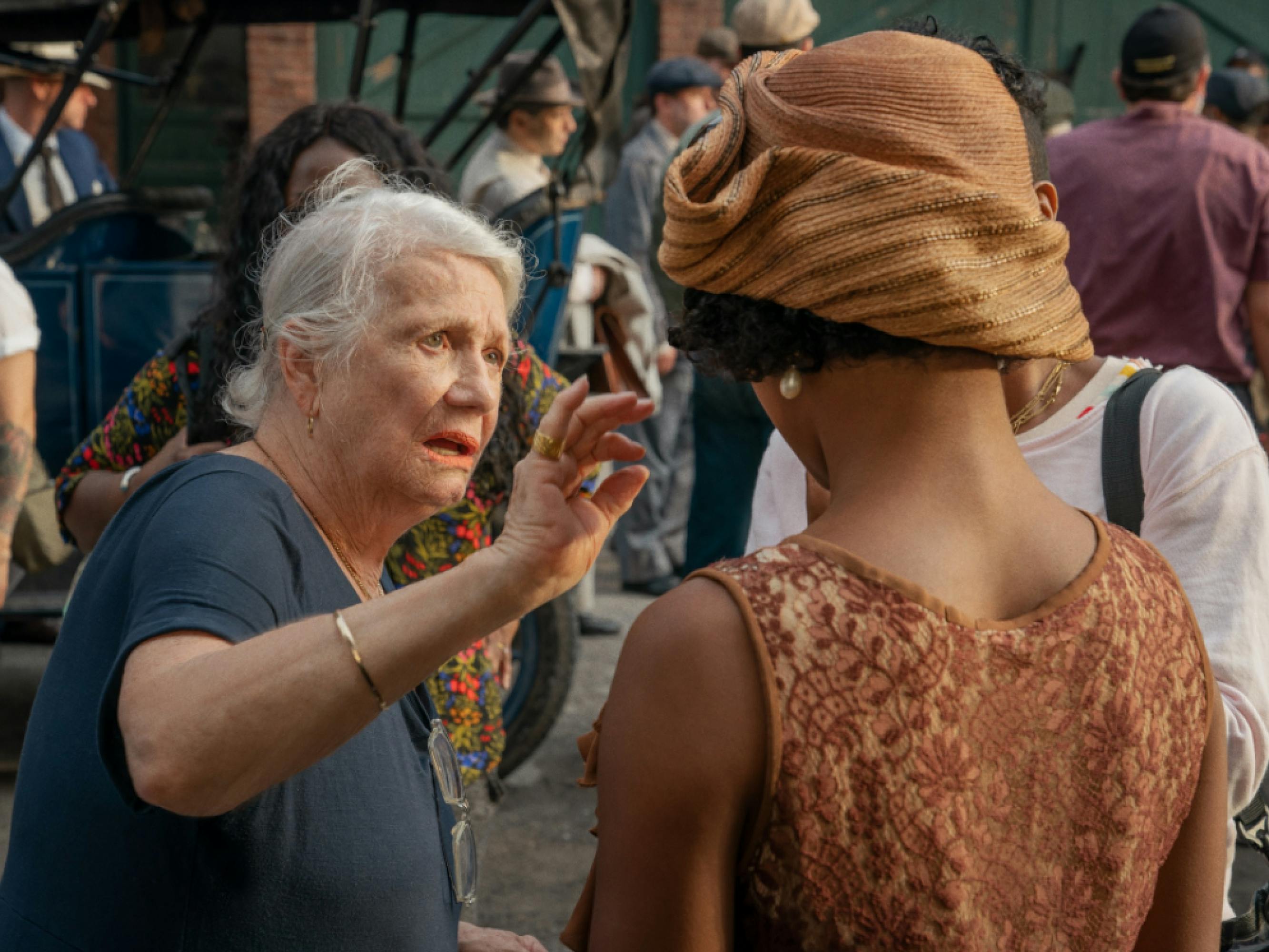 Costume designer Ann Roth looks over the costume of Dussie Mae actor Taylour Paige. A busy set lives and breathes behind them. 