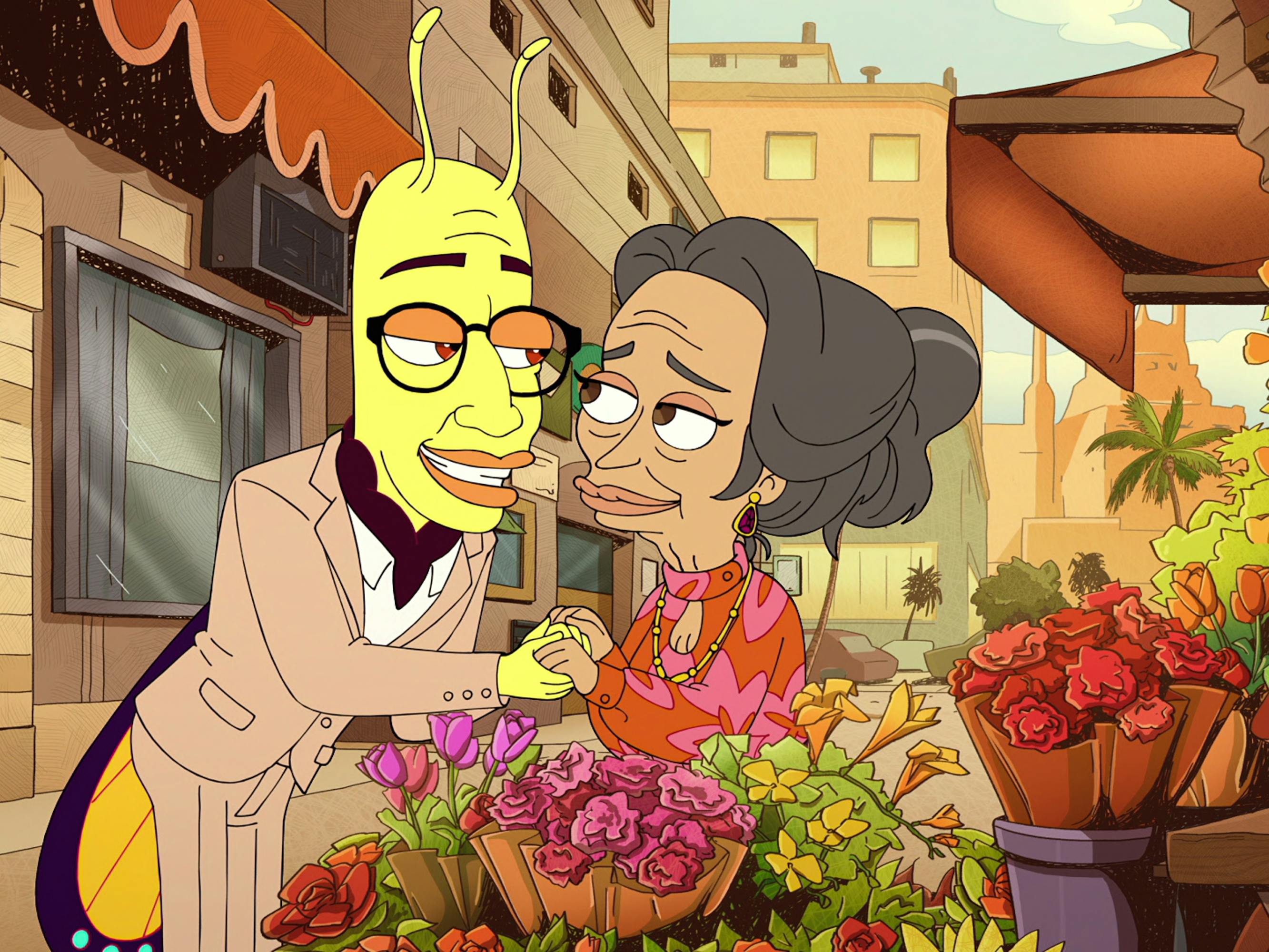 Walter the Lovebug (Brandon Kyle Goodman) and Yara (Nidah Barber-Raymond) embrace by a flower stand.