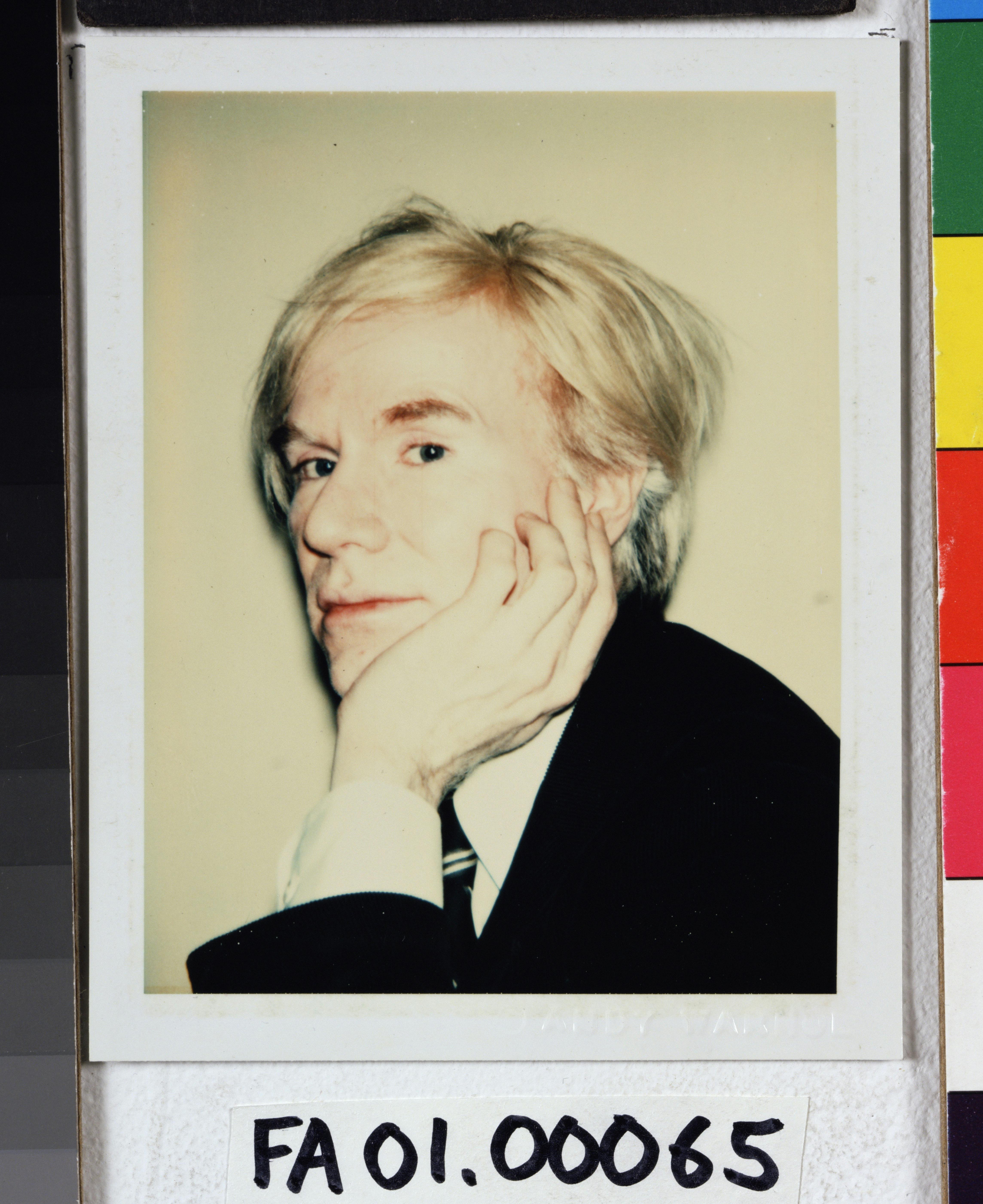 A polaroid of Andy Warhol in a black jacket and white shirt resting his chin on his palm. The bottom reads FA 0100065.