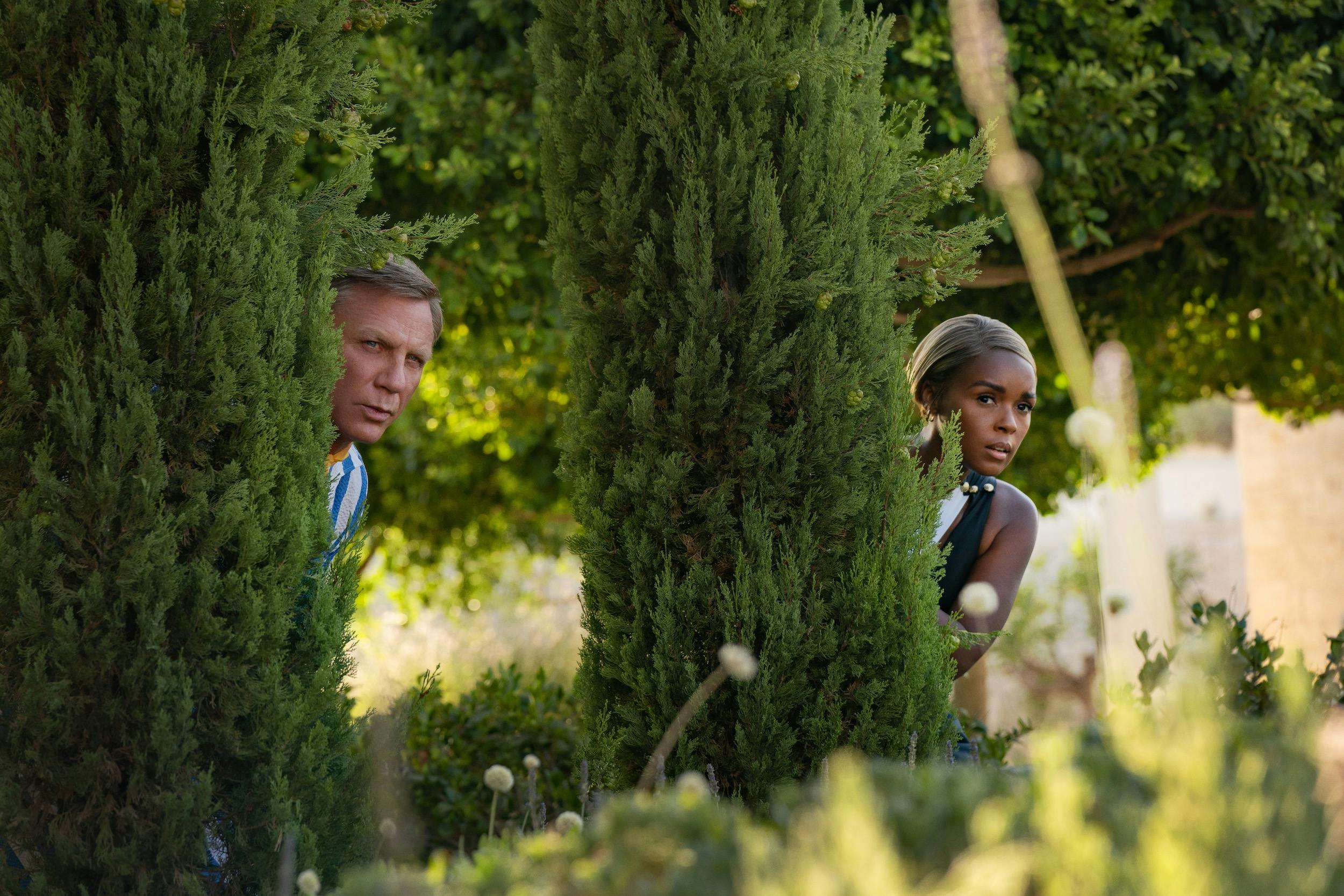 Daniel Craig and Janelle Monáe creep behind trees in this verdant scene.