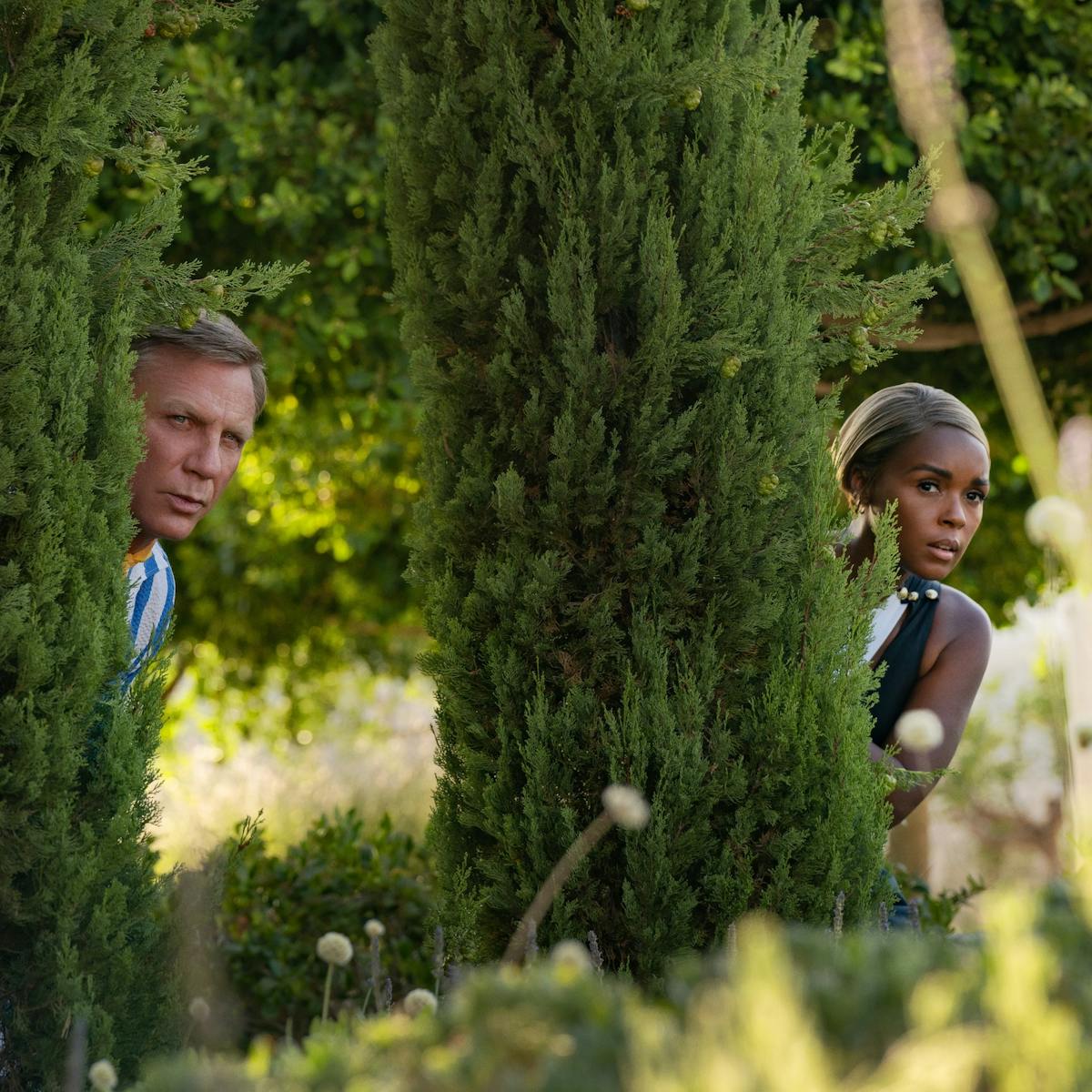 Daniel Craig and Janelle Monáe creep behind trees in this verdant scene.