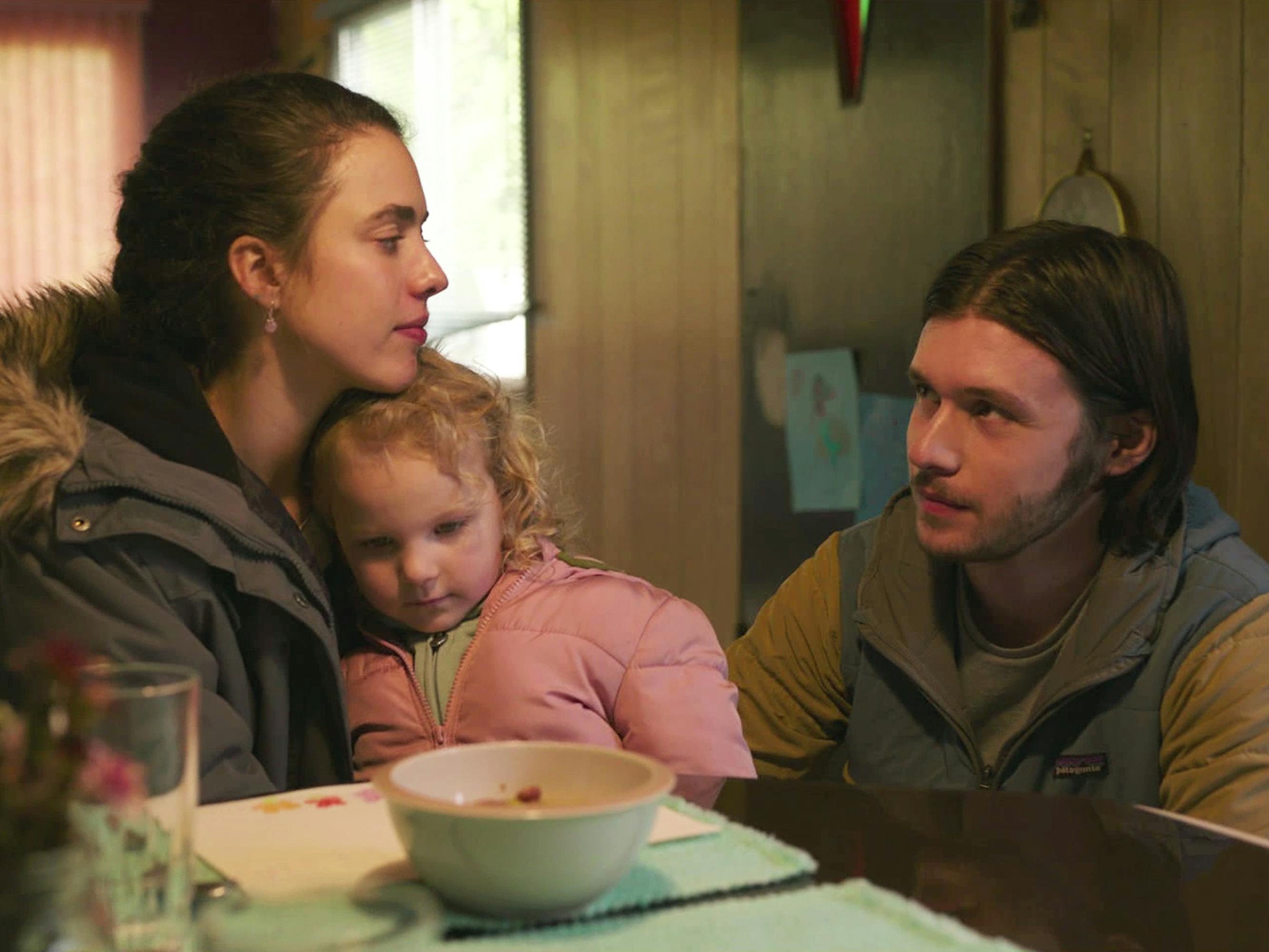 Alex Russell (Margaret Qualley), Maddy Boyd (Rylea Nevaeh Whittet), and Sean Boyd (Nick Robinson) sit at a turquoise table. Alex wears a grey puffer, Maddy wears a pink puffer, and Sean wears a brown-blue jacket.