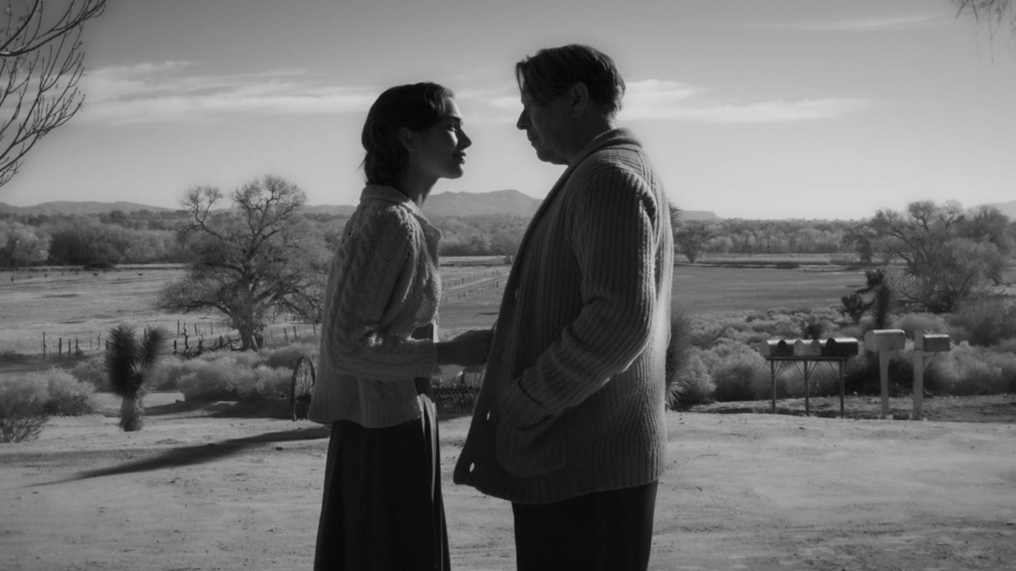 Lily Collins shares a scene with Mank co-star Gary Oldman. They are silhouetted against a desert landscape, wearing the most luscious cable-knit sweaters.