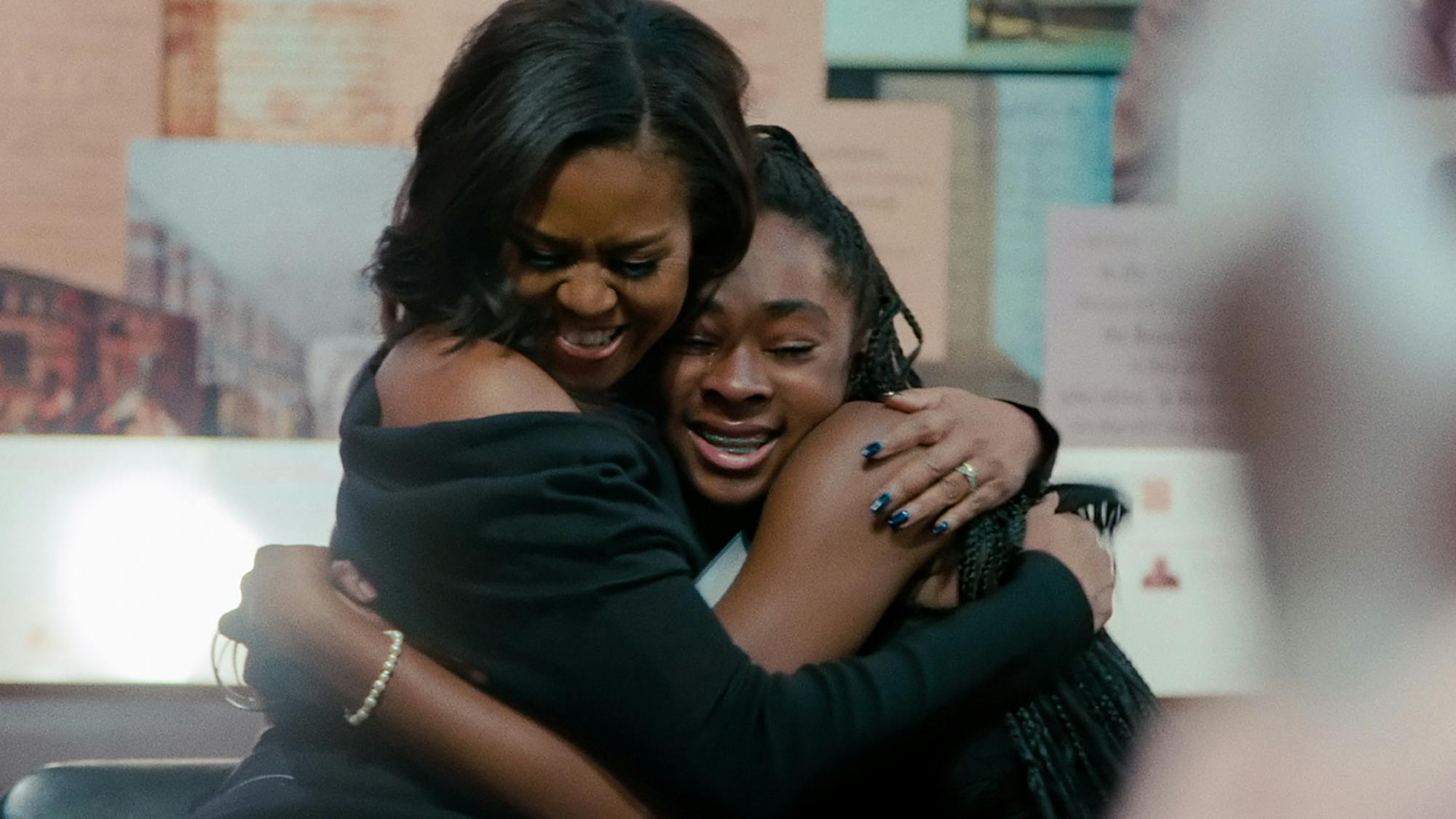 The first lady smiles as she pulls a student into a tight hug. 