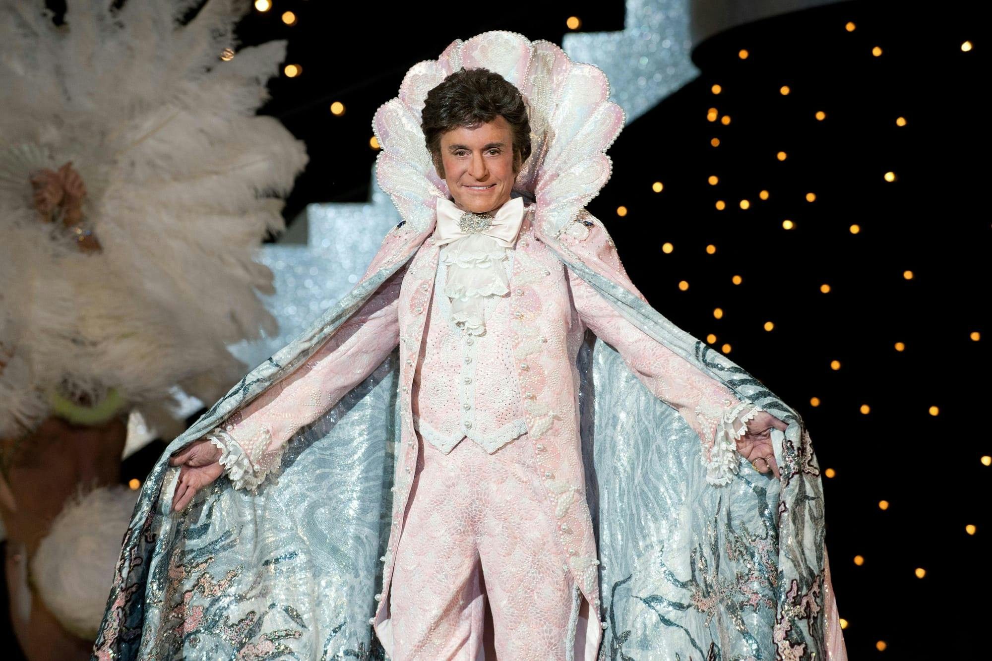 Liberace (Michael Douglas) in Behind the Candelabra wears an ornate pink costume and collar, complete with a light blue cape.