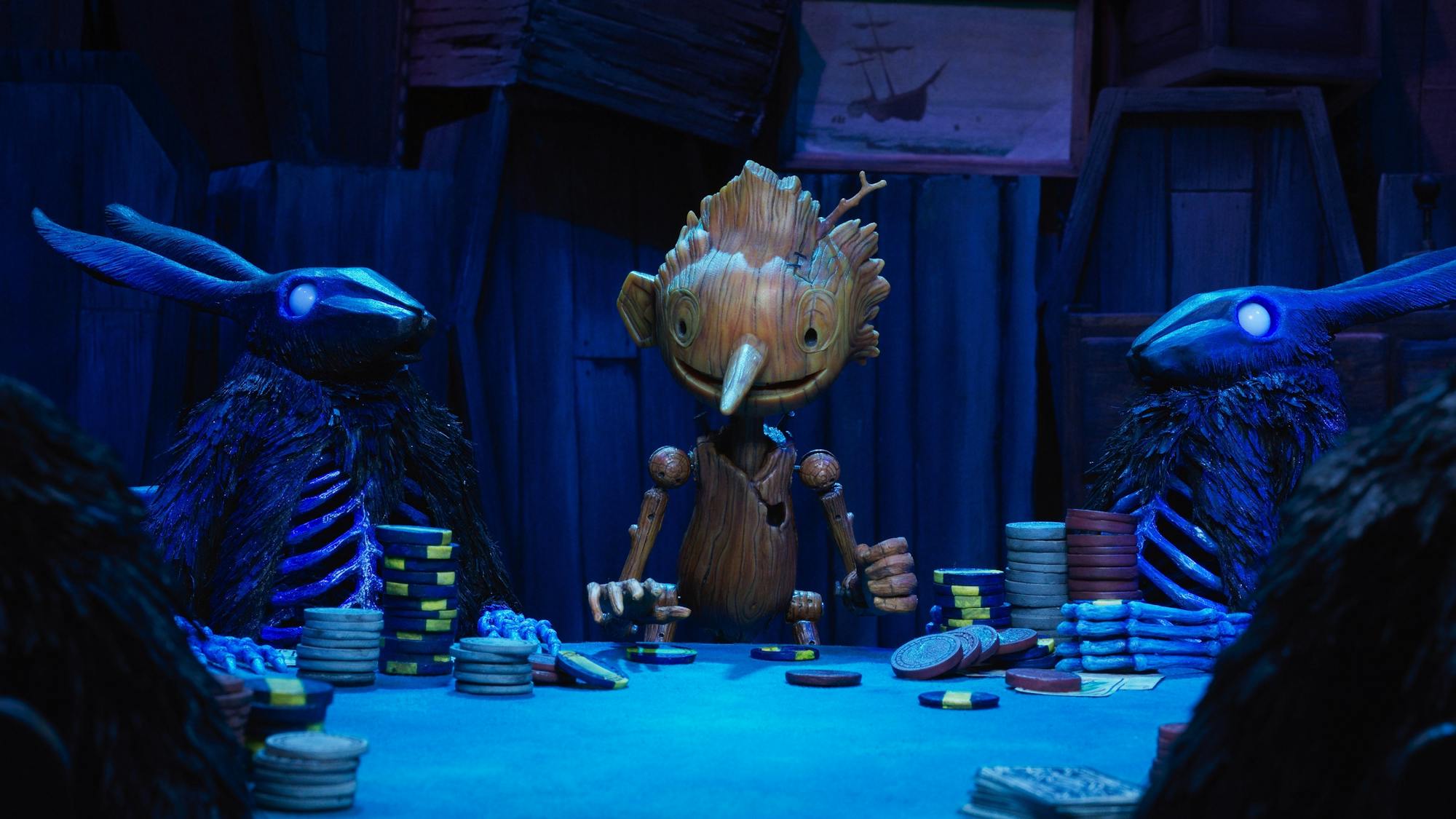 Pinocchio (Gregory Mann) plays poker with the Black Rabbits (Tim Blake Nelson) in this blue-lit scene.