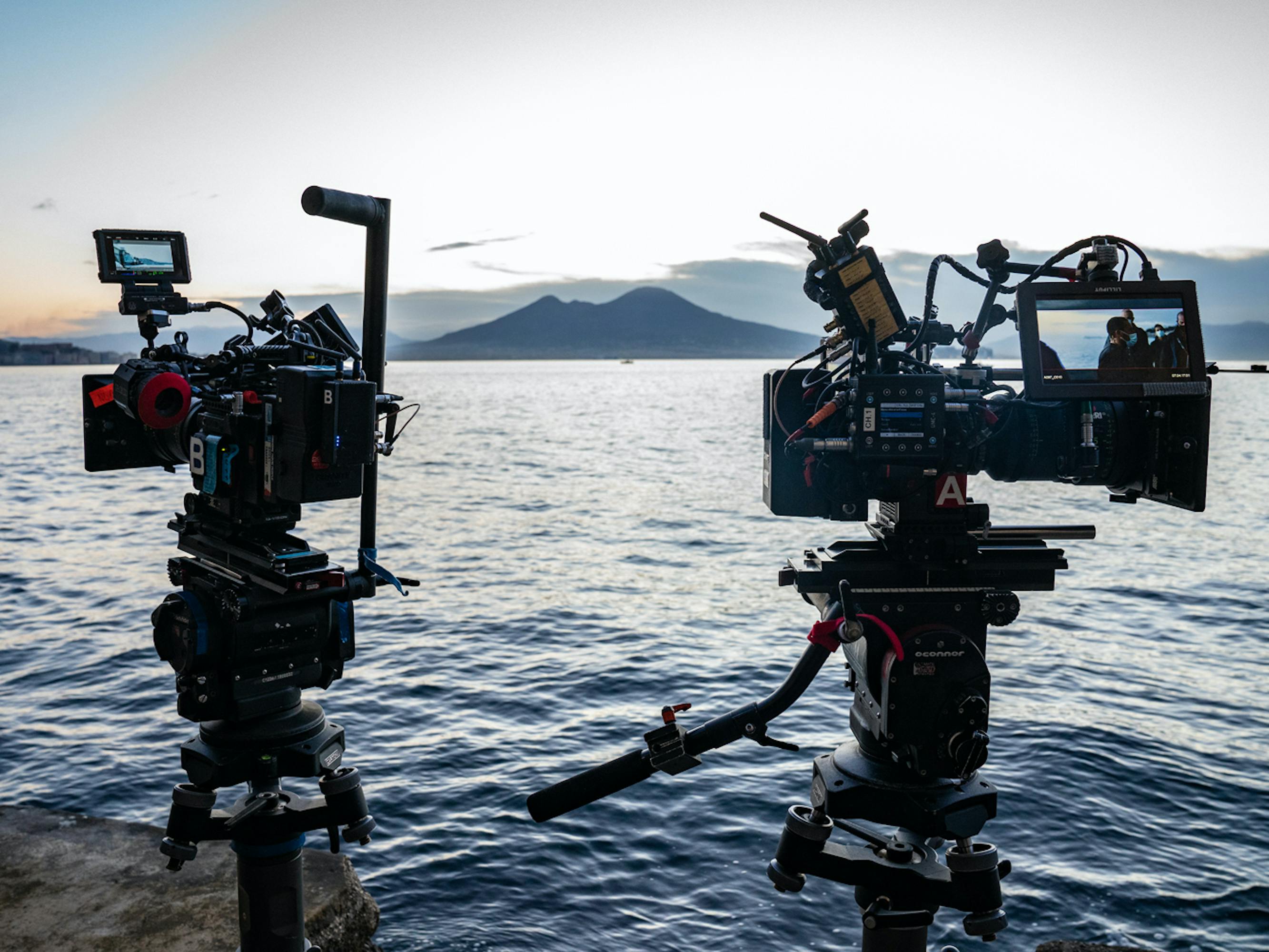 Two cameras are propped up in the middle of the water. The dark ripples show the sun is setting.