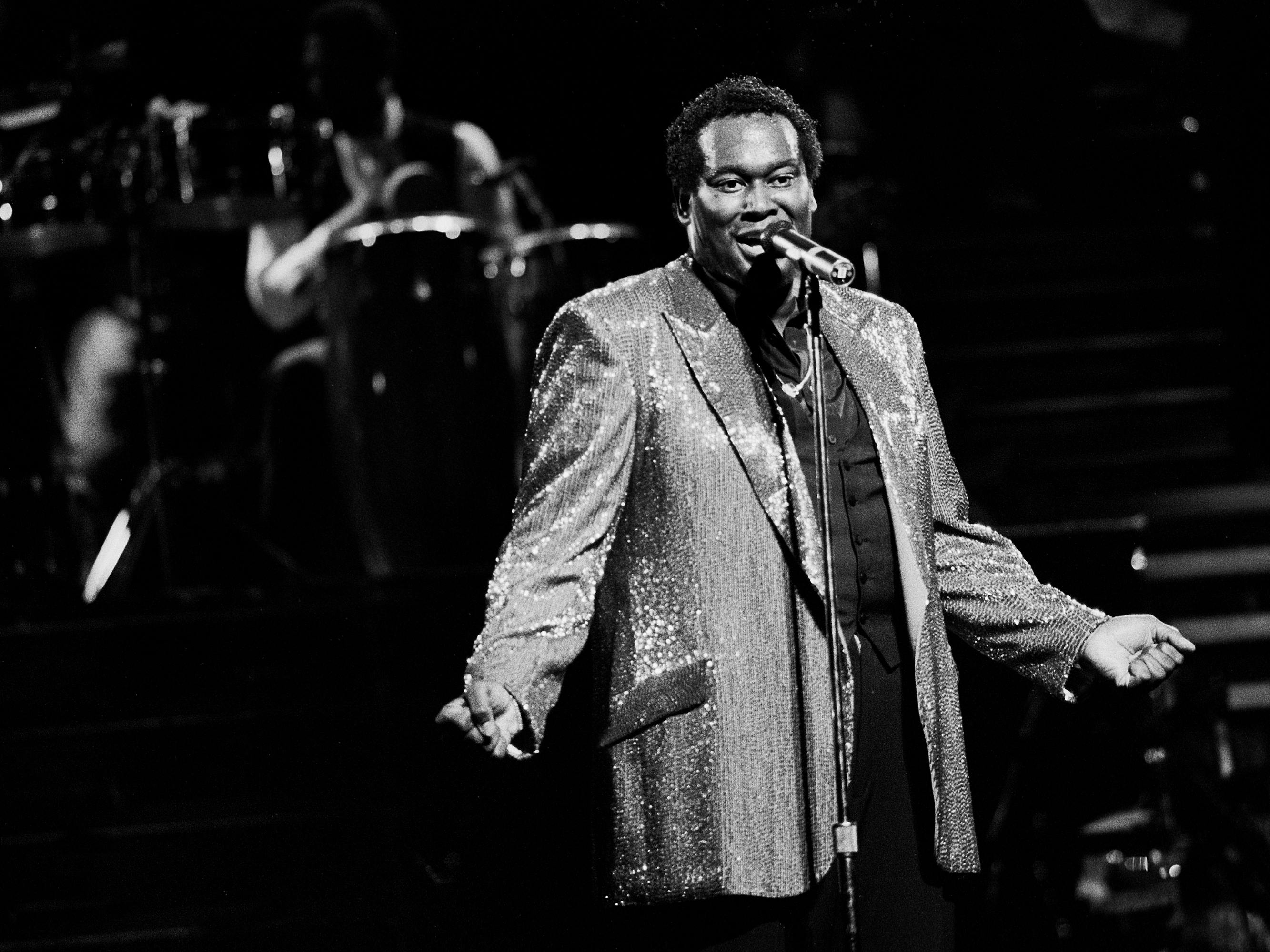 Luther Vandross at the Aire Crown Theater in Chicago Illinois in January 12, 1984. Vandross sings into a microphone and wears a sparkly blazer.